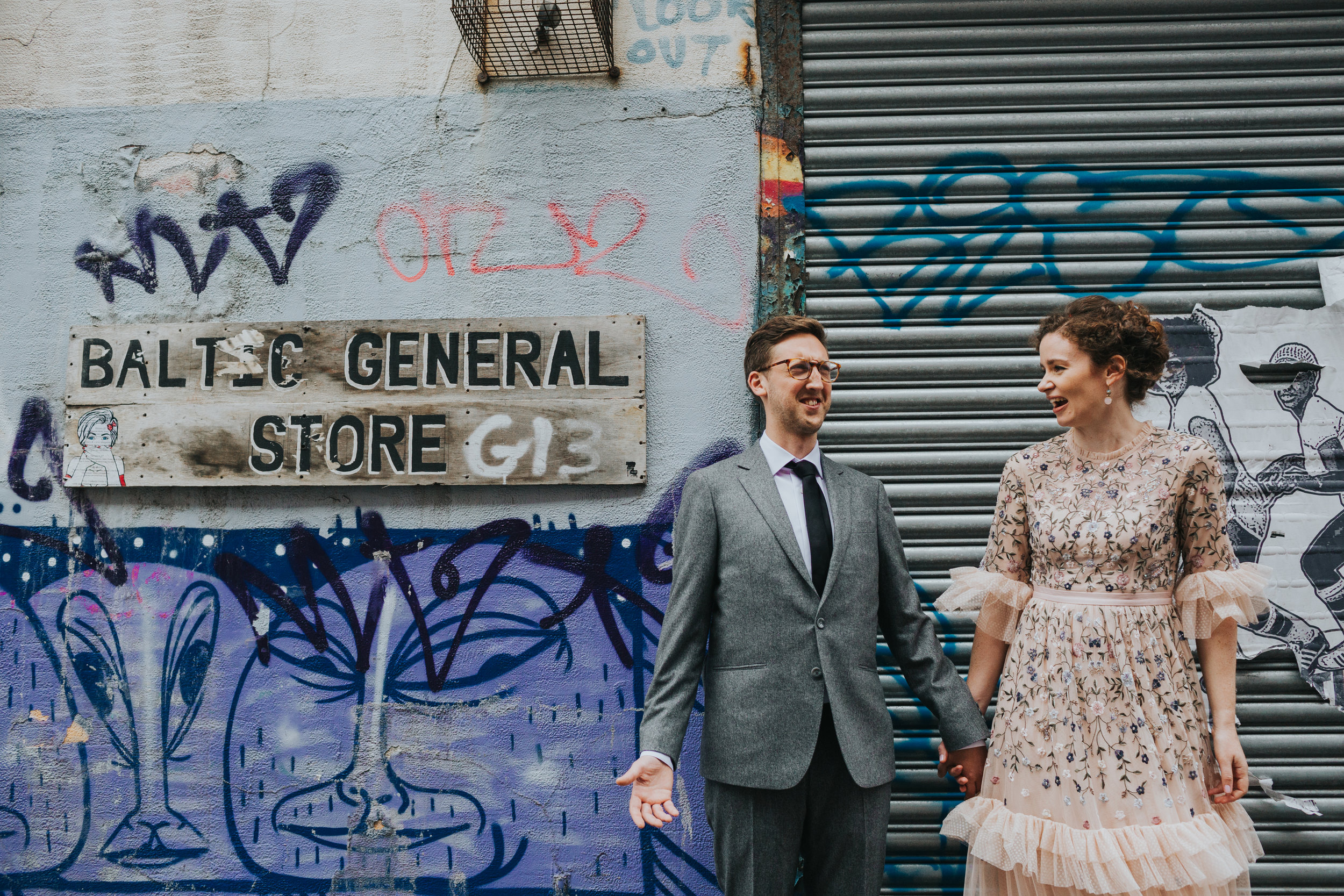 Bride and Groom laugh together besides Baltic General Store Sign. 