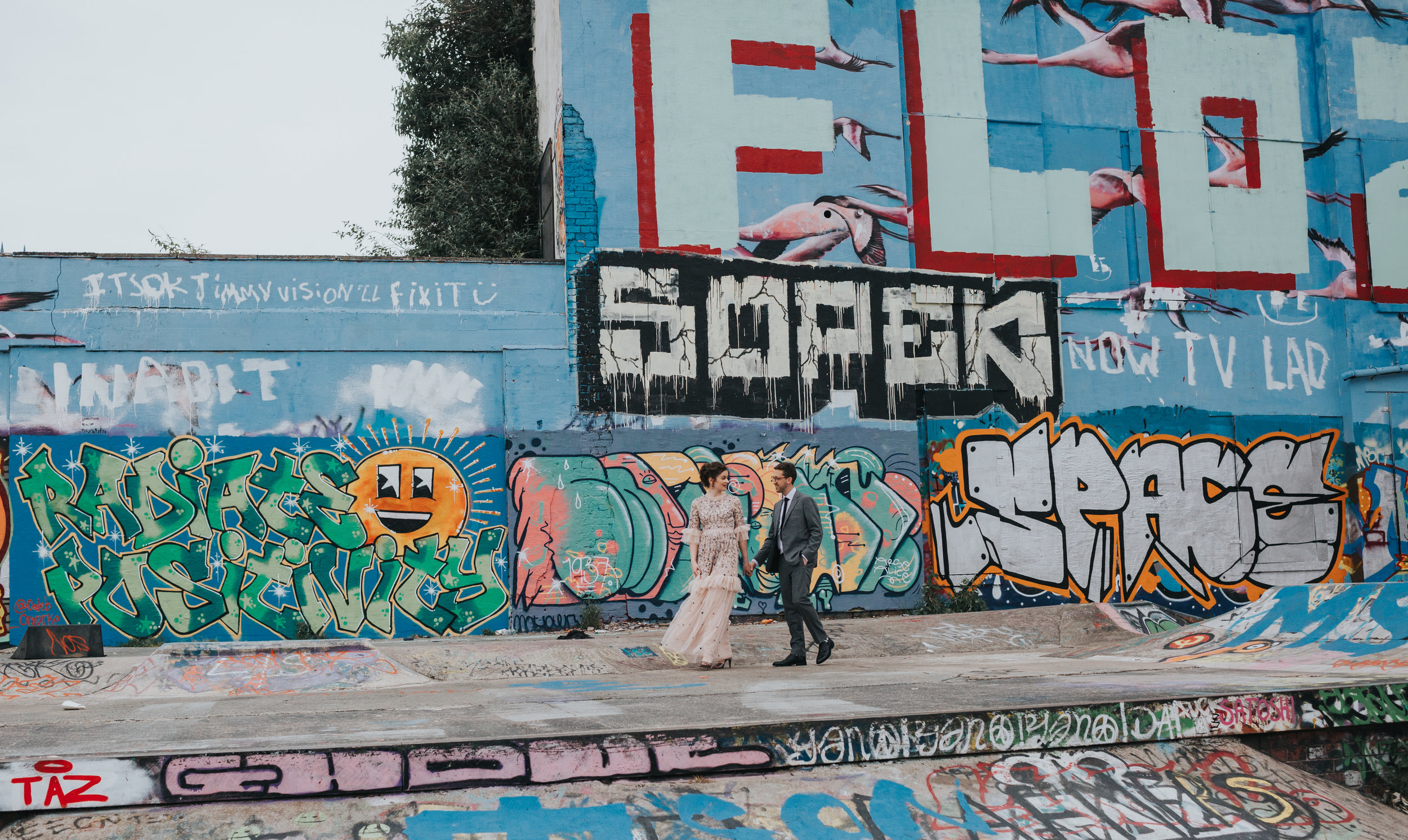 Bride and Groom walk through skate park together. 