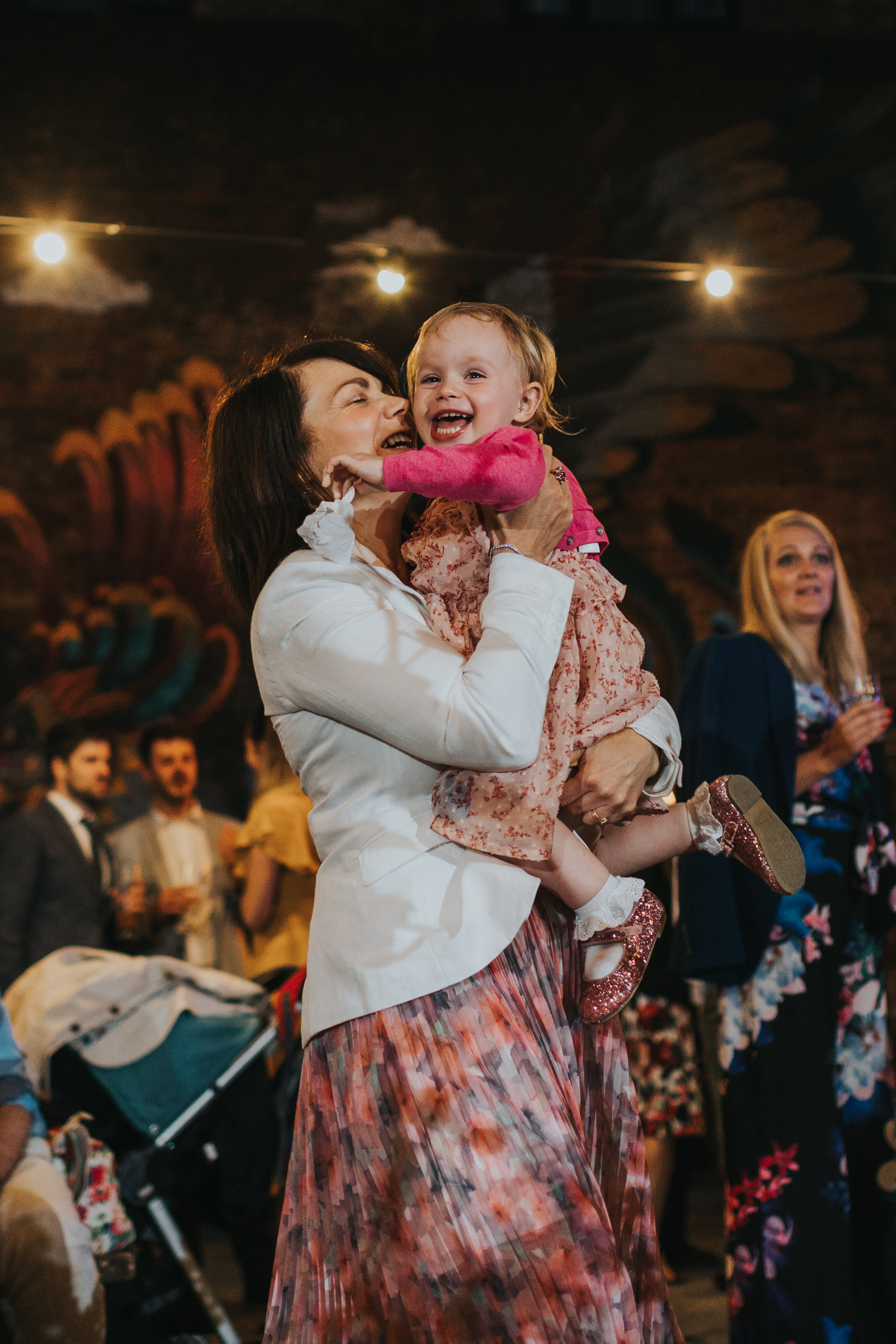 Little girl cheers excited as her mum picks her up.