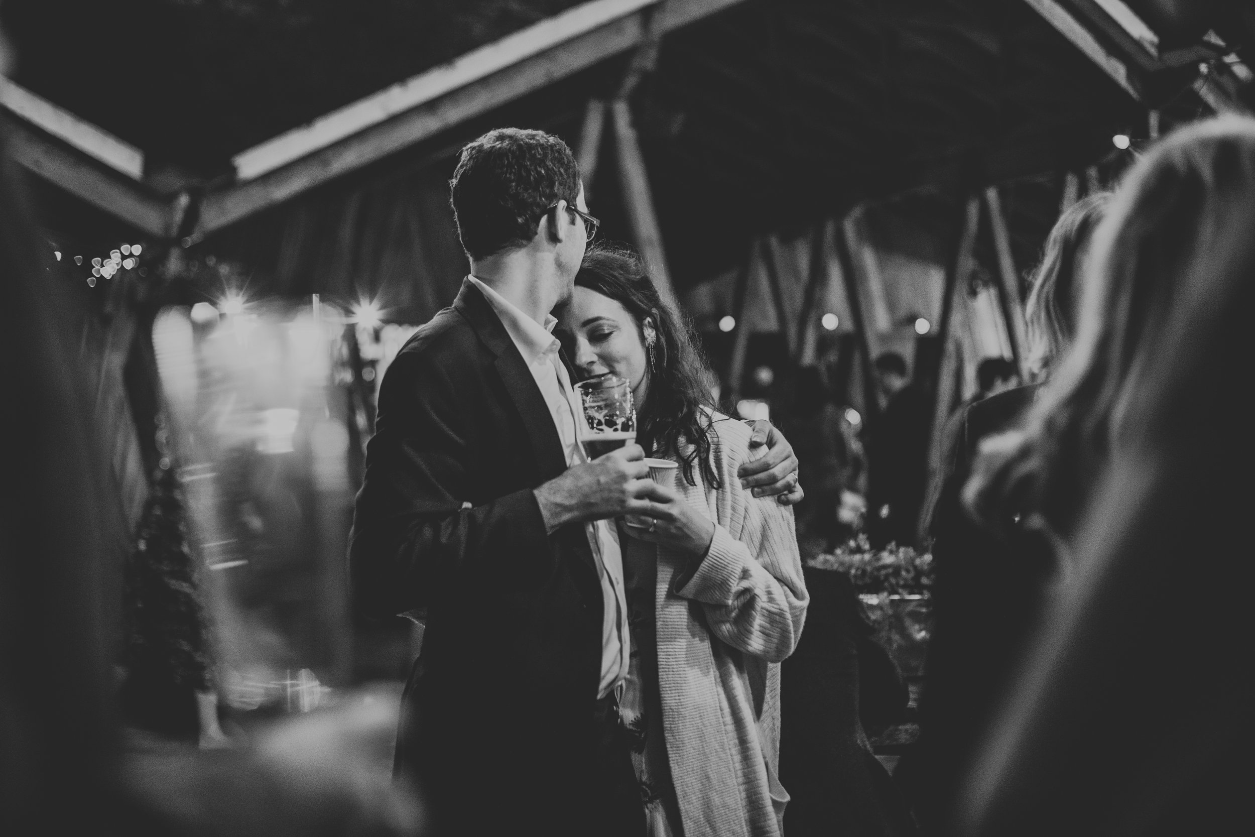 A couple have a cuddle unaware of the sneaky photographer. Photo in black and white.