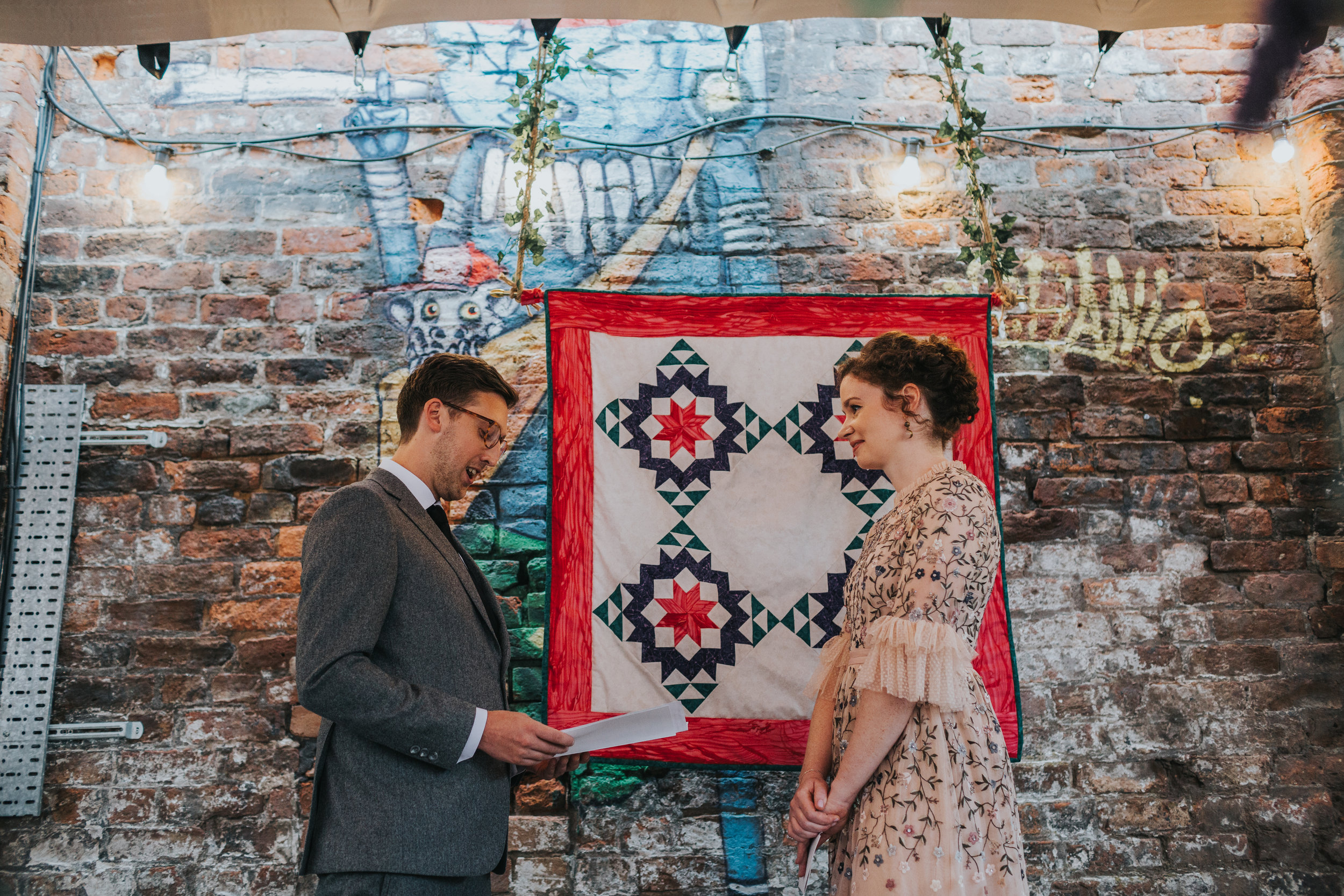 Bride and groom say their vows in front of a patch work blanket. 