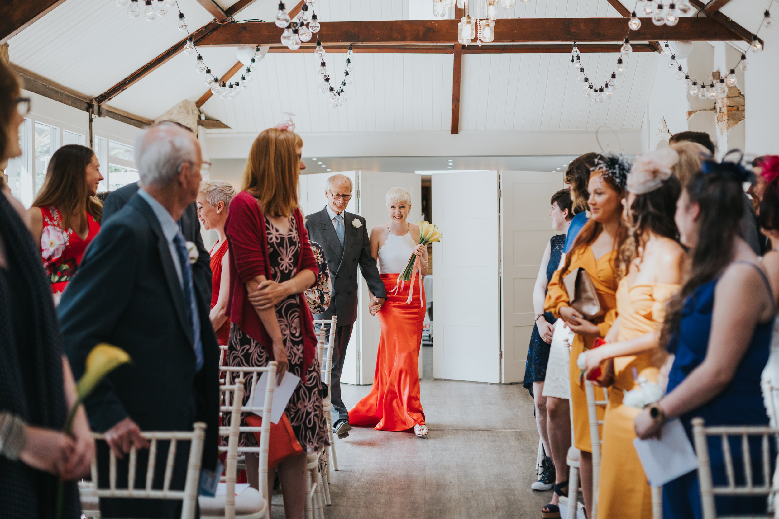 Bride is walked down the aisle by her father. 