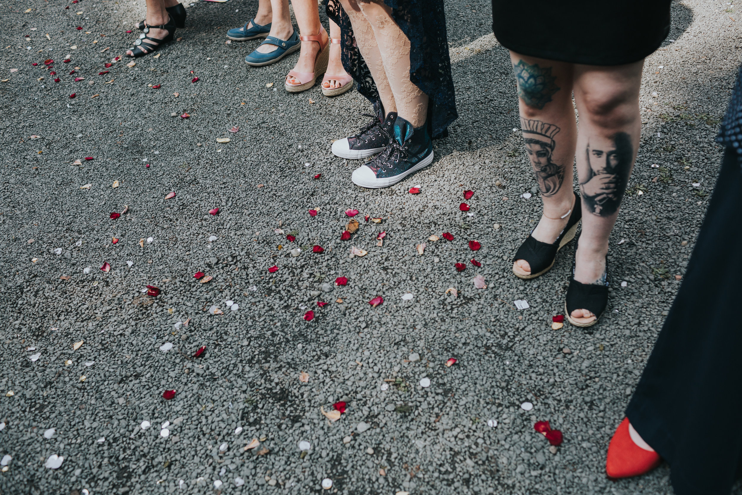 Natural petal confetti on the floor next to guests tattooed legs. 