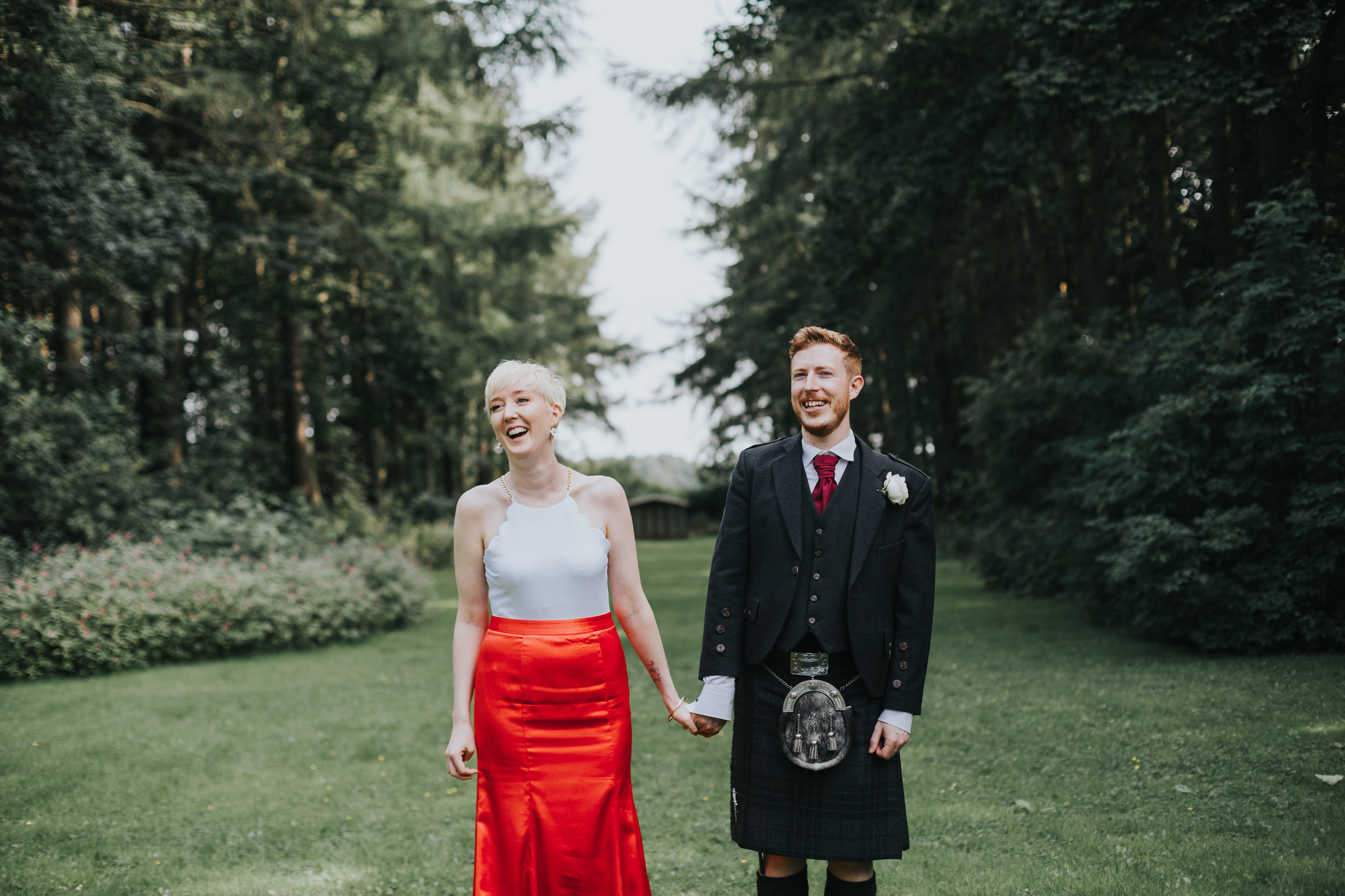 Bride and groom laugh at wedding guests. 