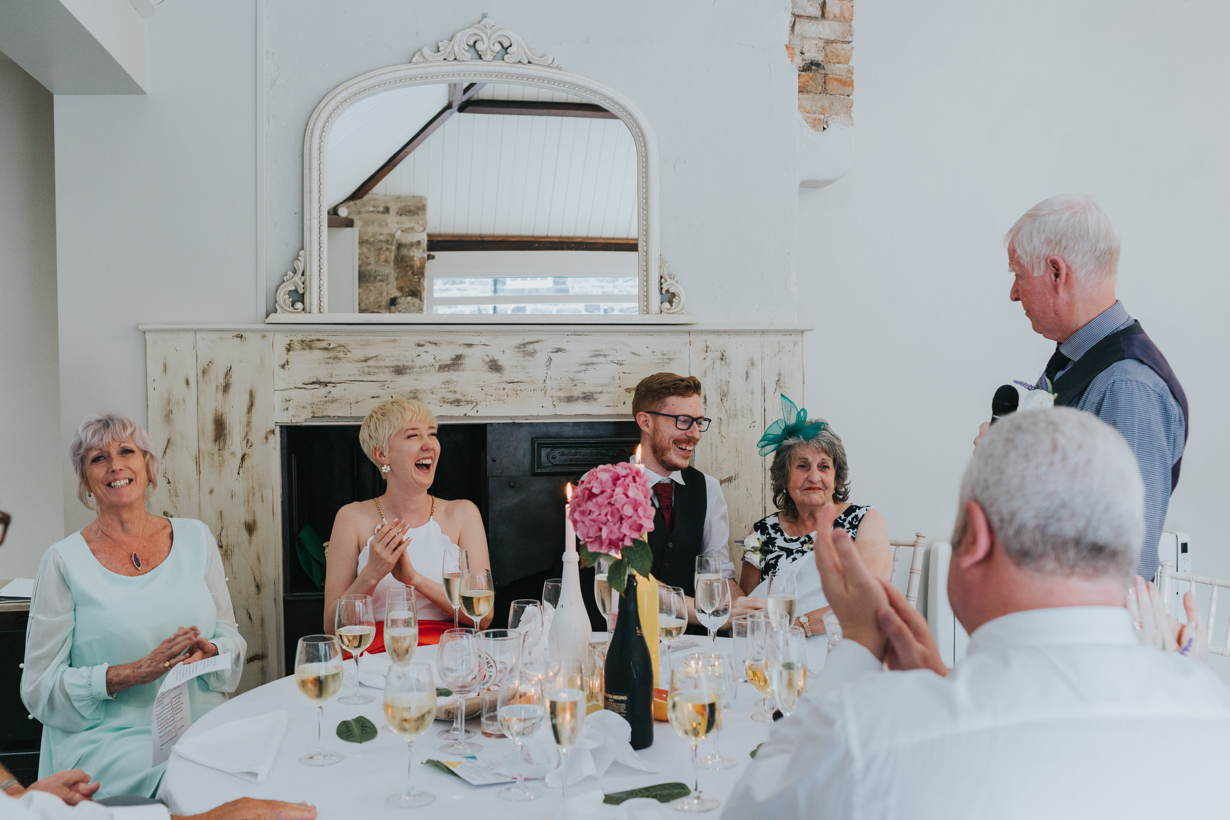 Bride, groom, mother of the bride and the grooms grandma laugh and the grooms grandads speech. 