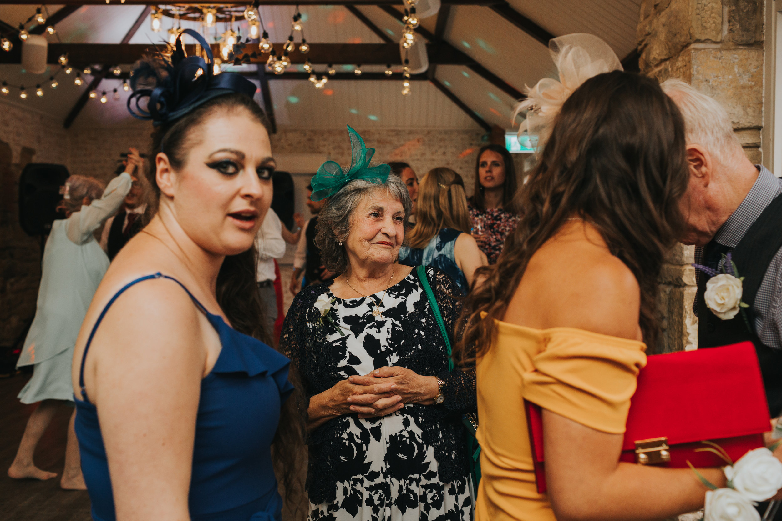 The grooms grandma watches the dancing smiling. 