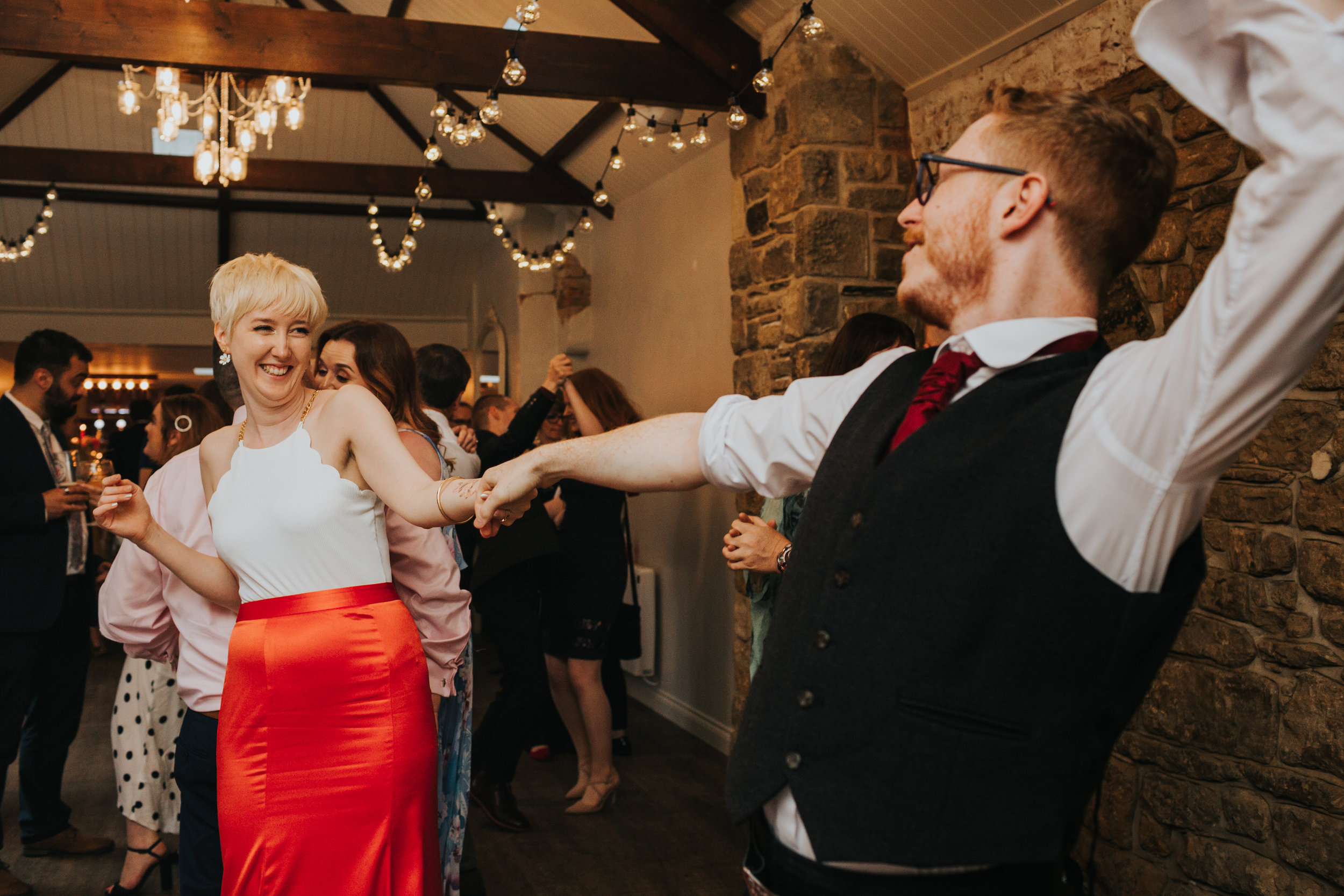 Bride and groom laughing and dancing together with their friends and family.