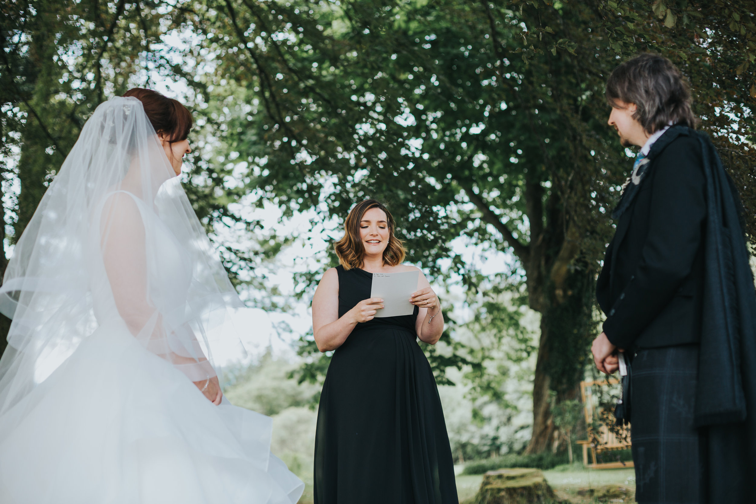 Wedding guests reads during ceremony as bride and groom look on. 