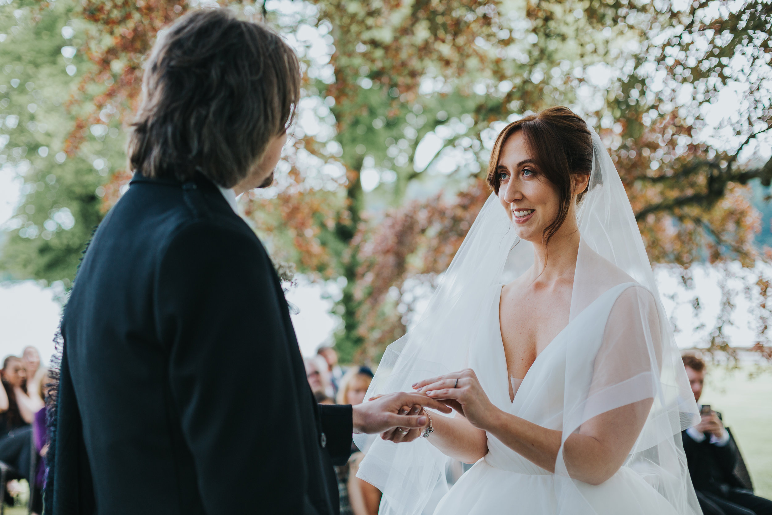 Bride puts ring on grooms finger. 