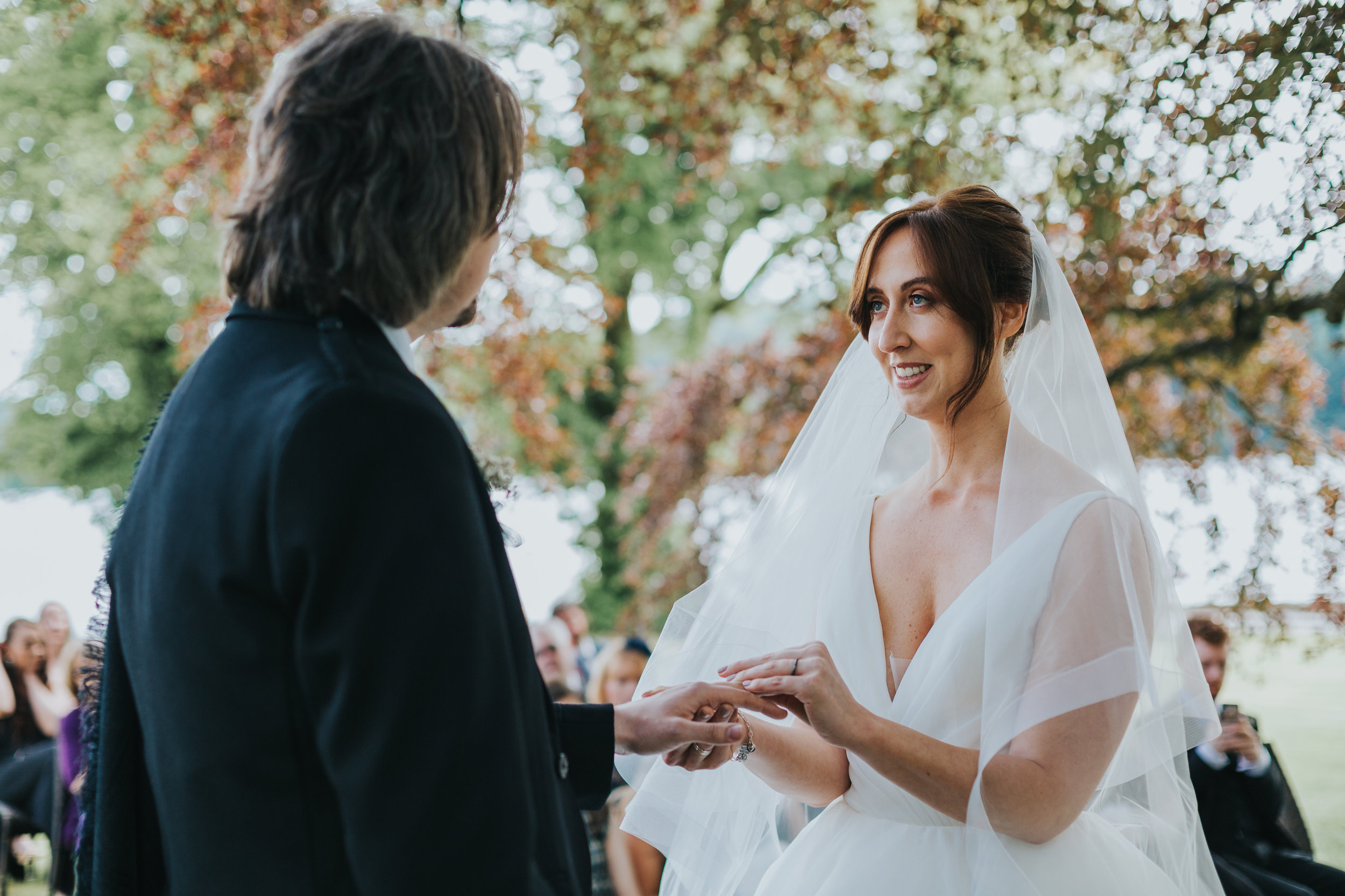 Bride puts ring on grooms finger.