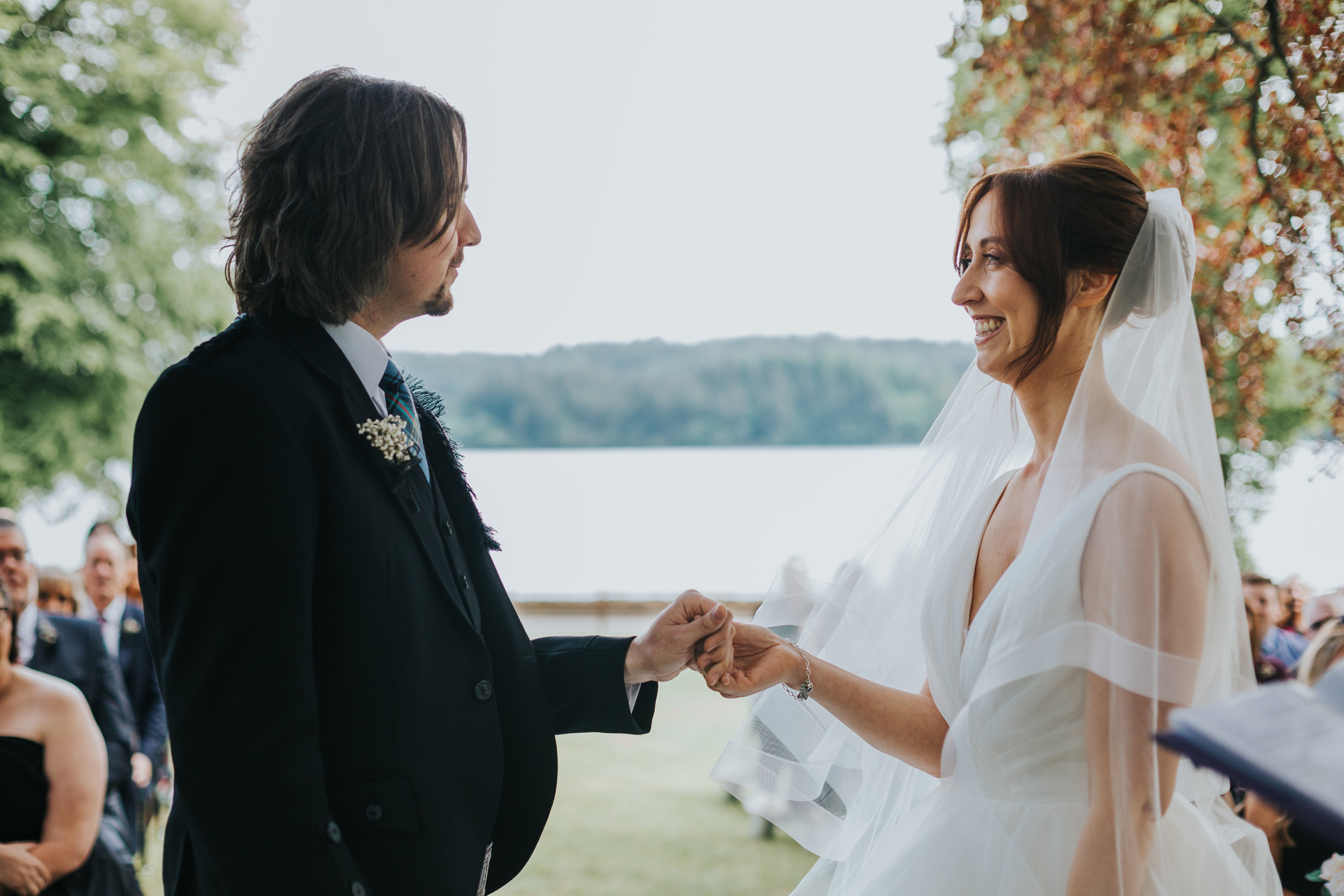 Bride and kilted groom stand appreciating one and other. 