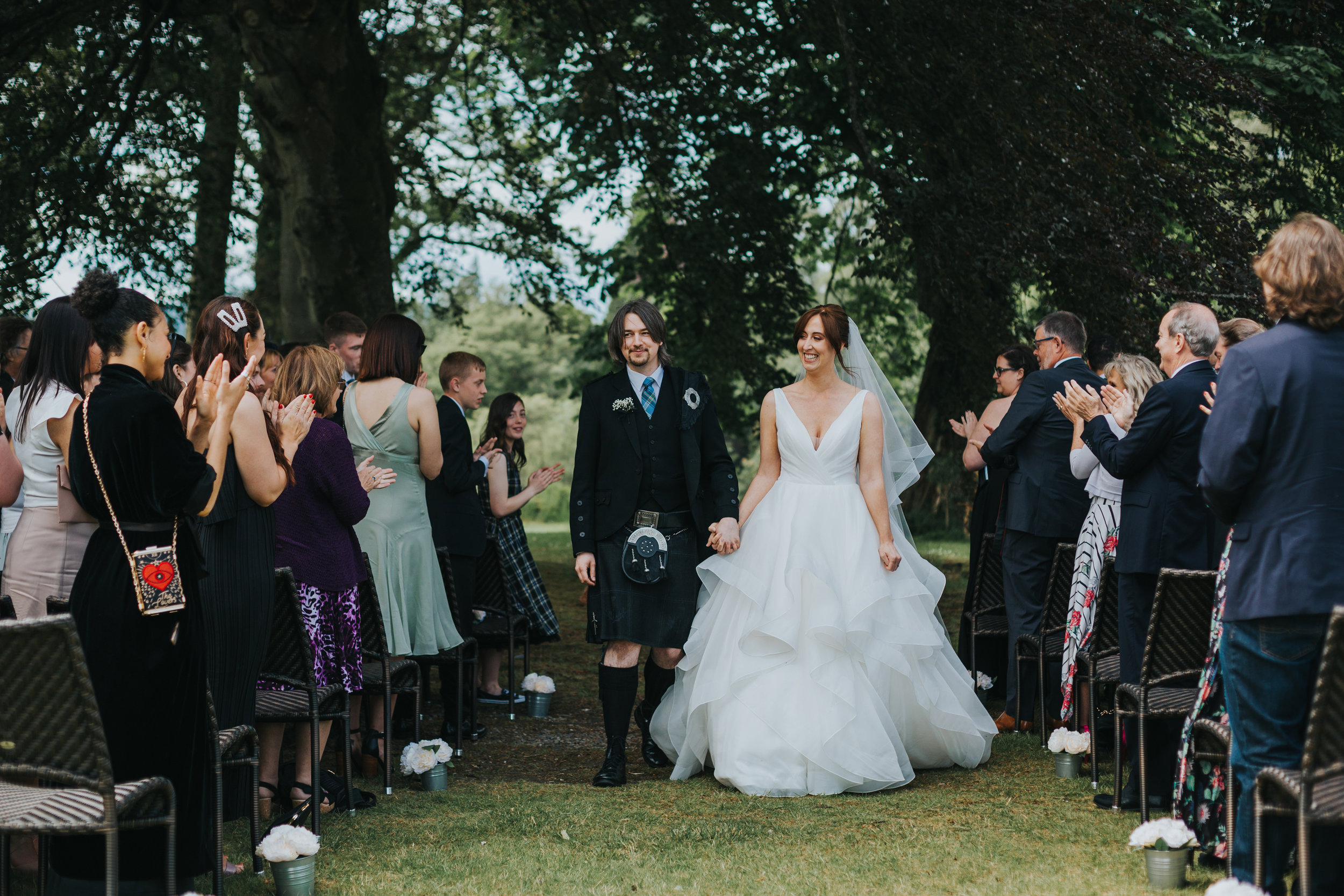 Bride and groom walk down the aisle smiling at their wedding guests. 