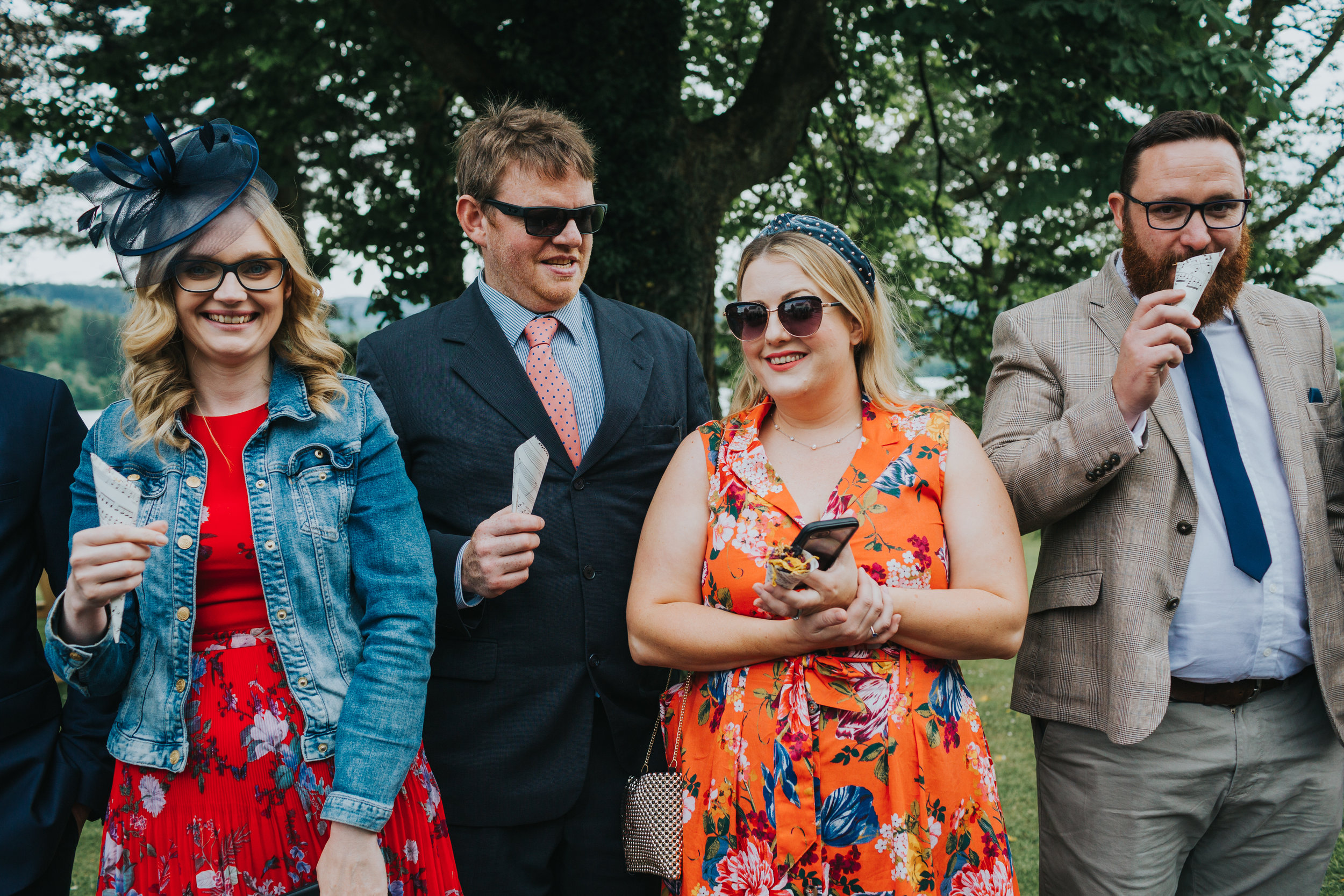 Brightly dressed wedding guests holding confetti.