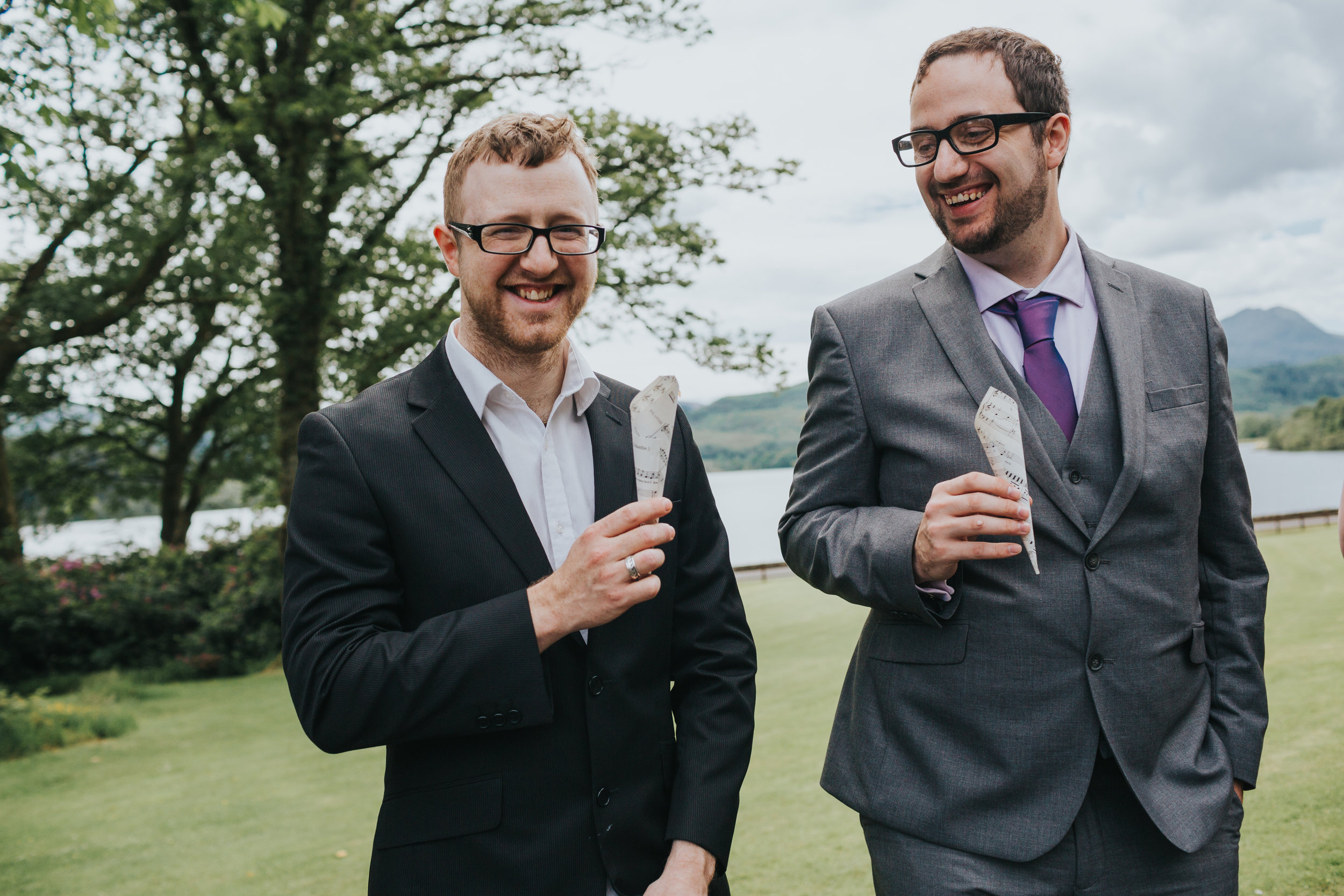 Smiling blokes holding confetti cones made from music sheet paper. 