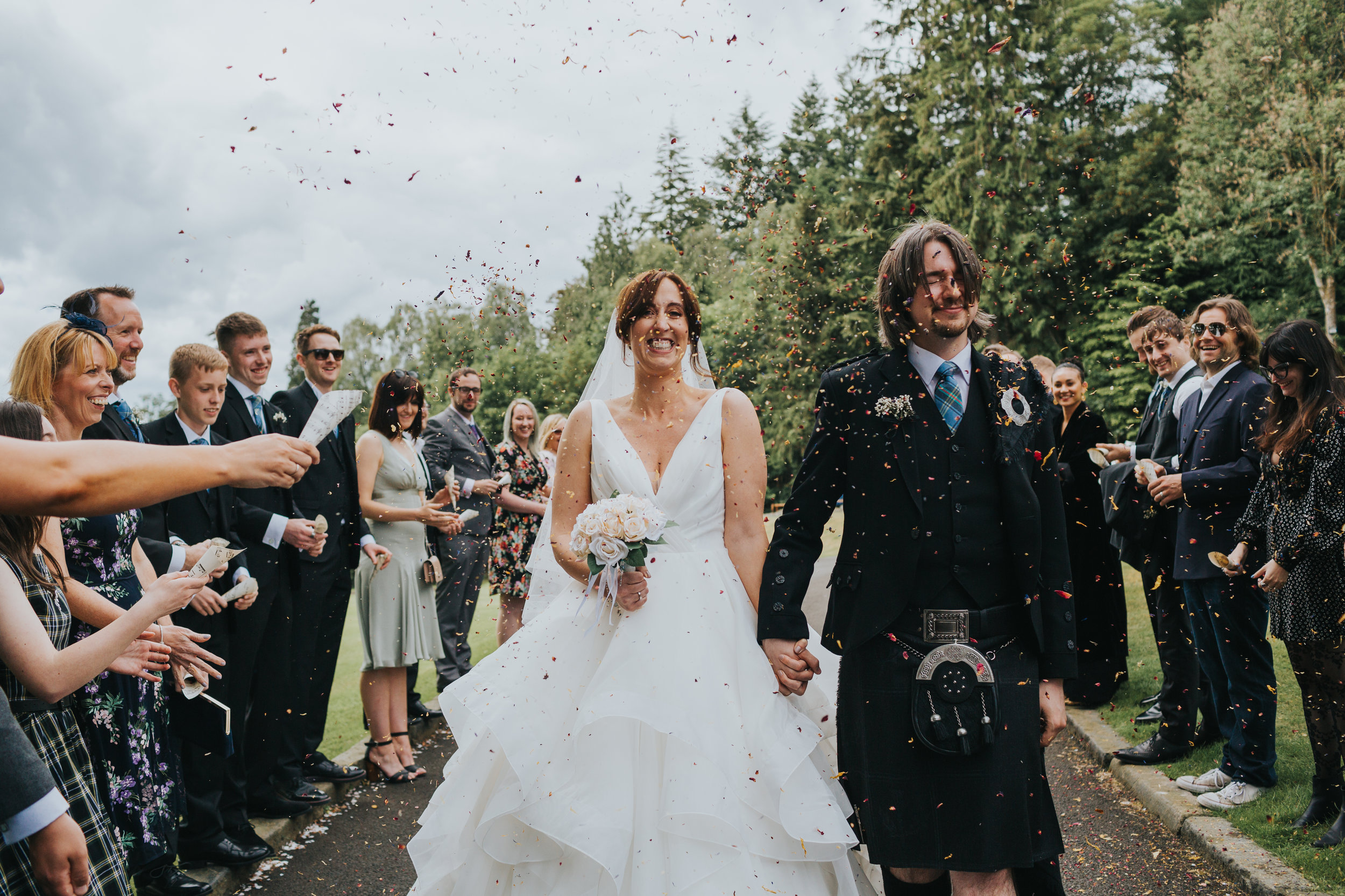Couple smile while confetti is thrown at them.