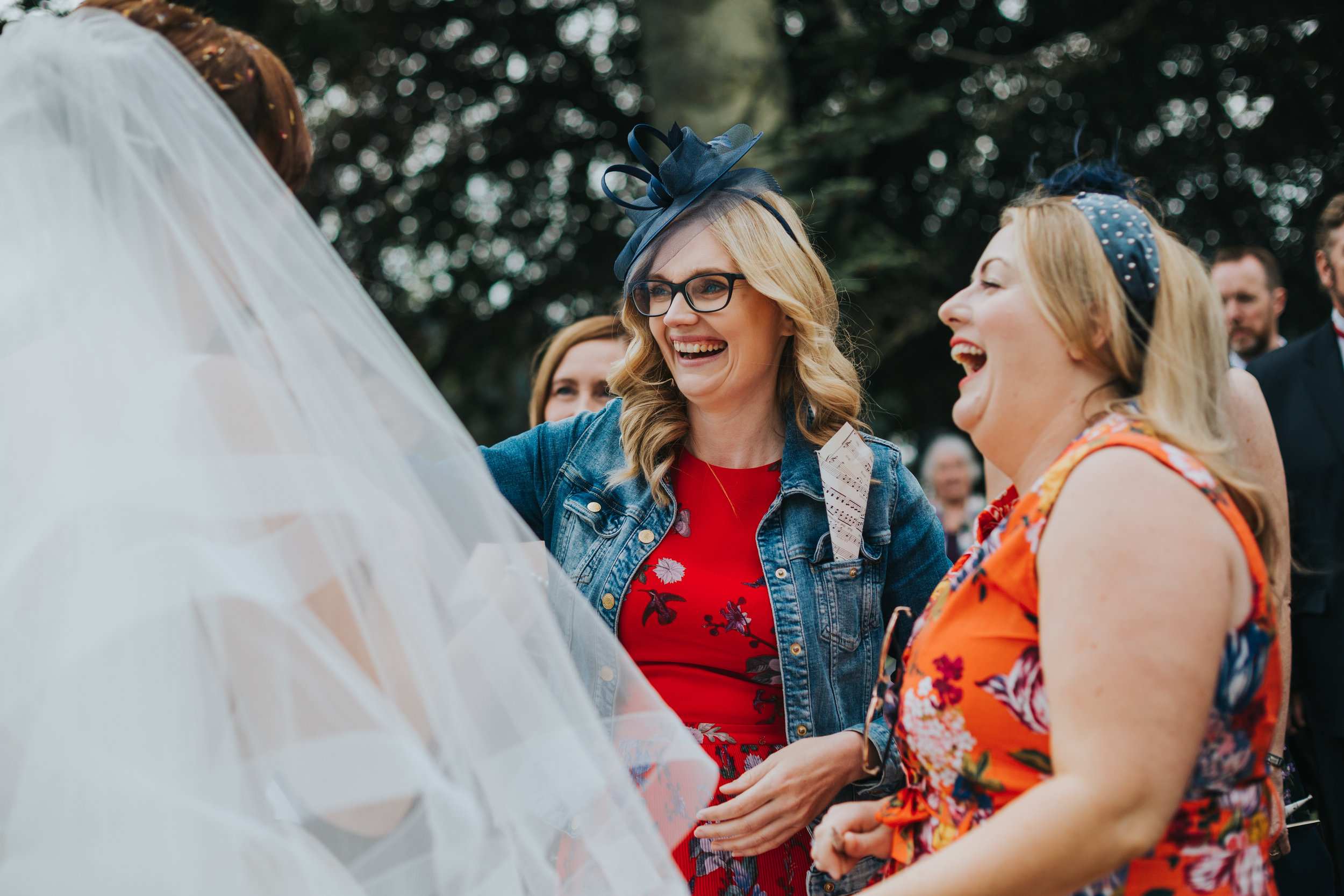 Brightly coloured wedding guests greet Bride. 