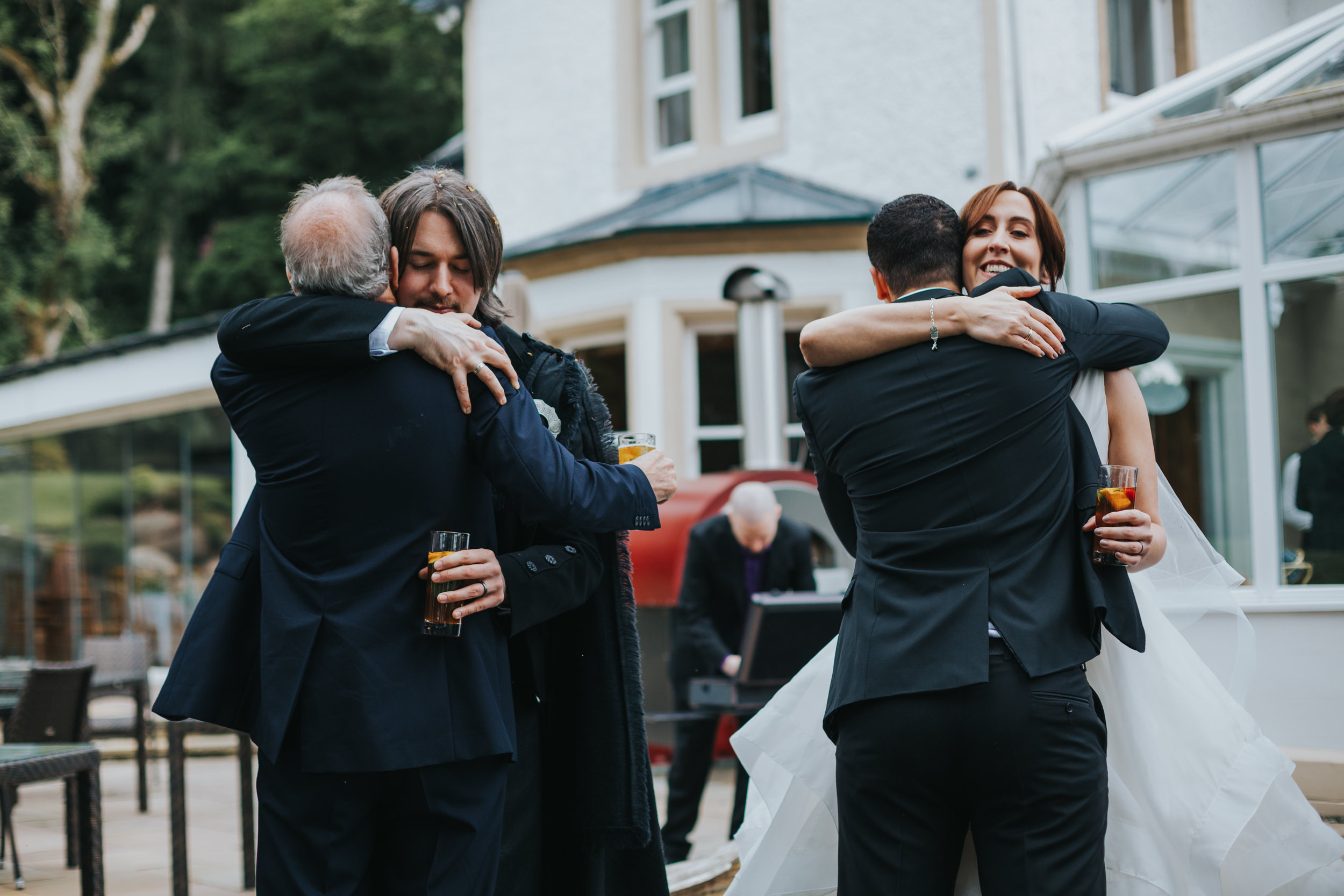 Bride and Groom hug wedding guests at the same time.