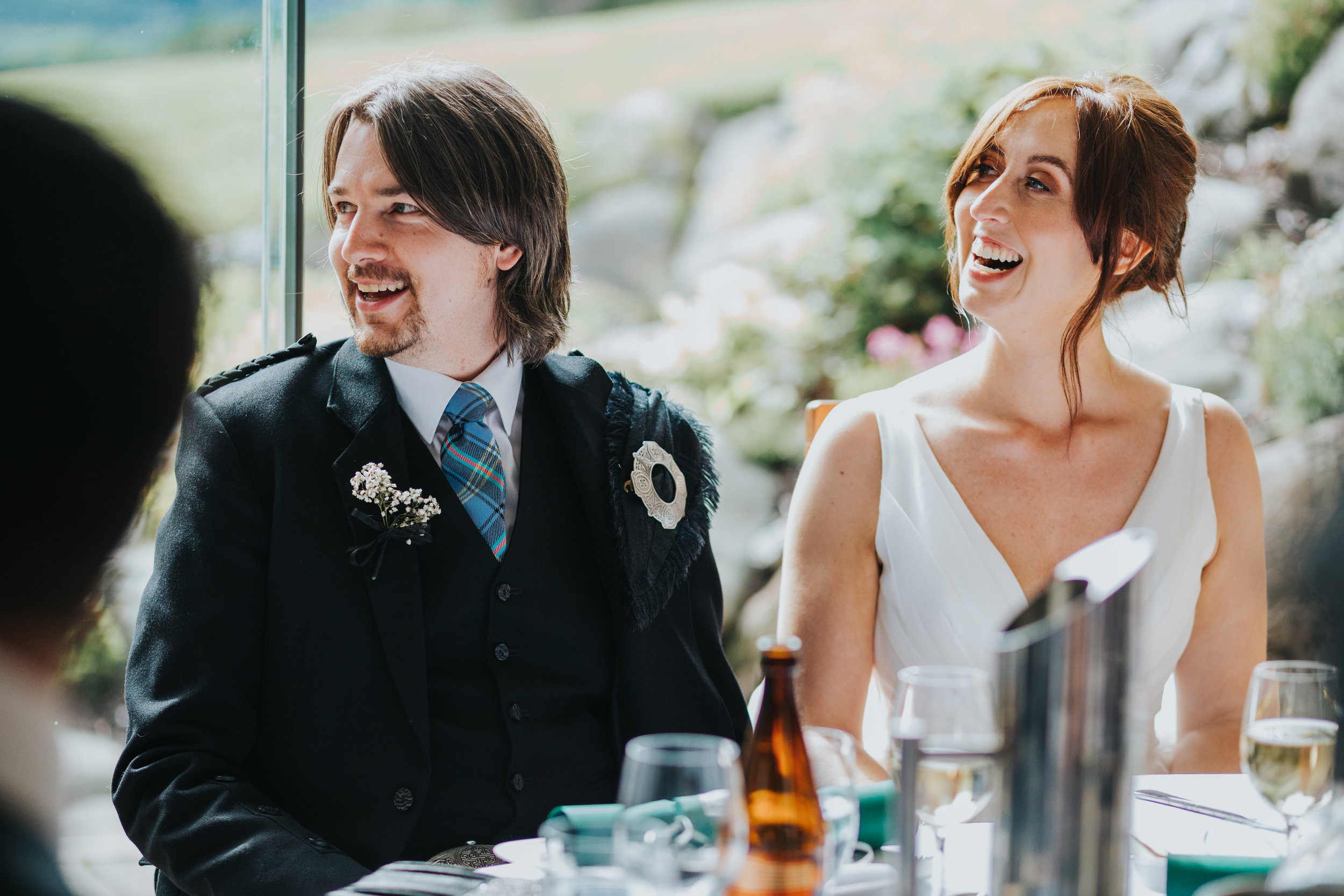 Bride and Groom laugh at speech. 
