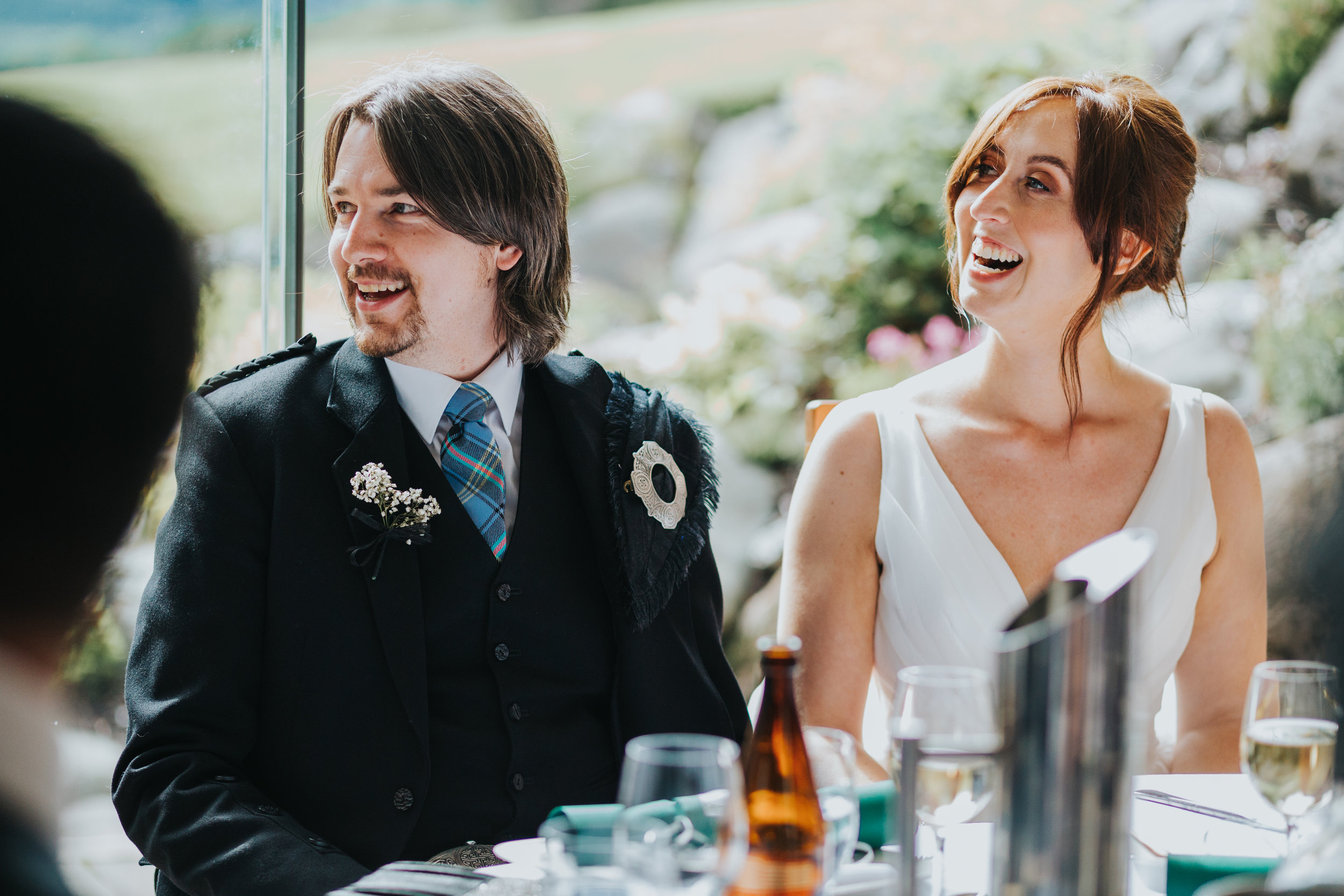 Bride and Groom laugh at speech.