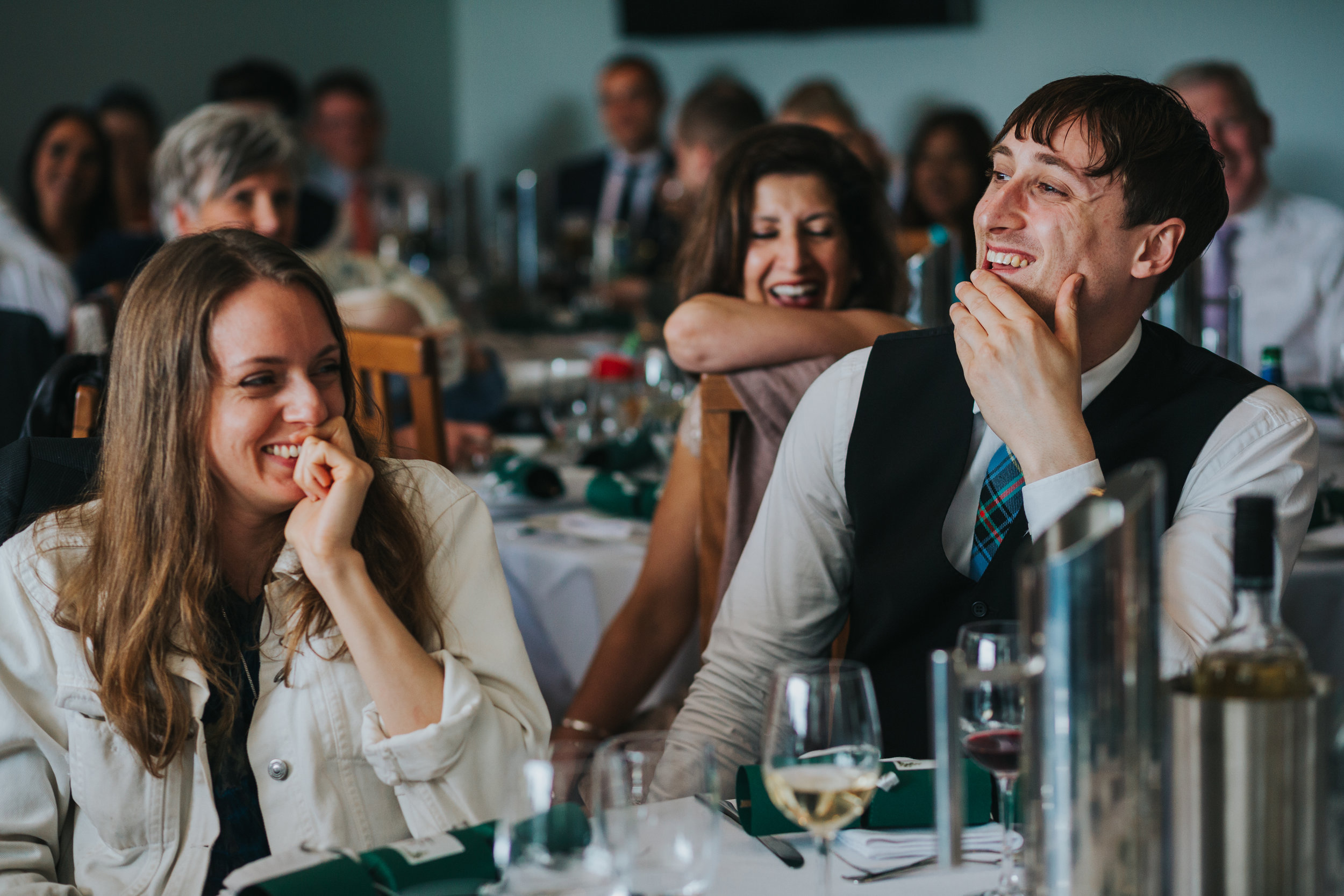 Wedding guests laugh at the grooms speech. 