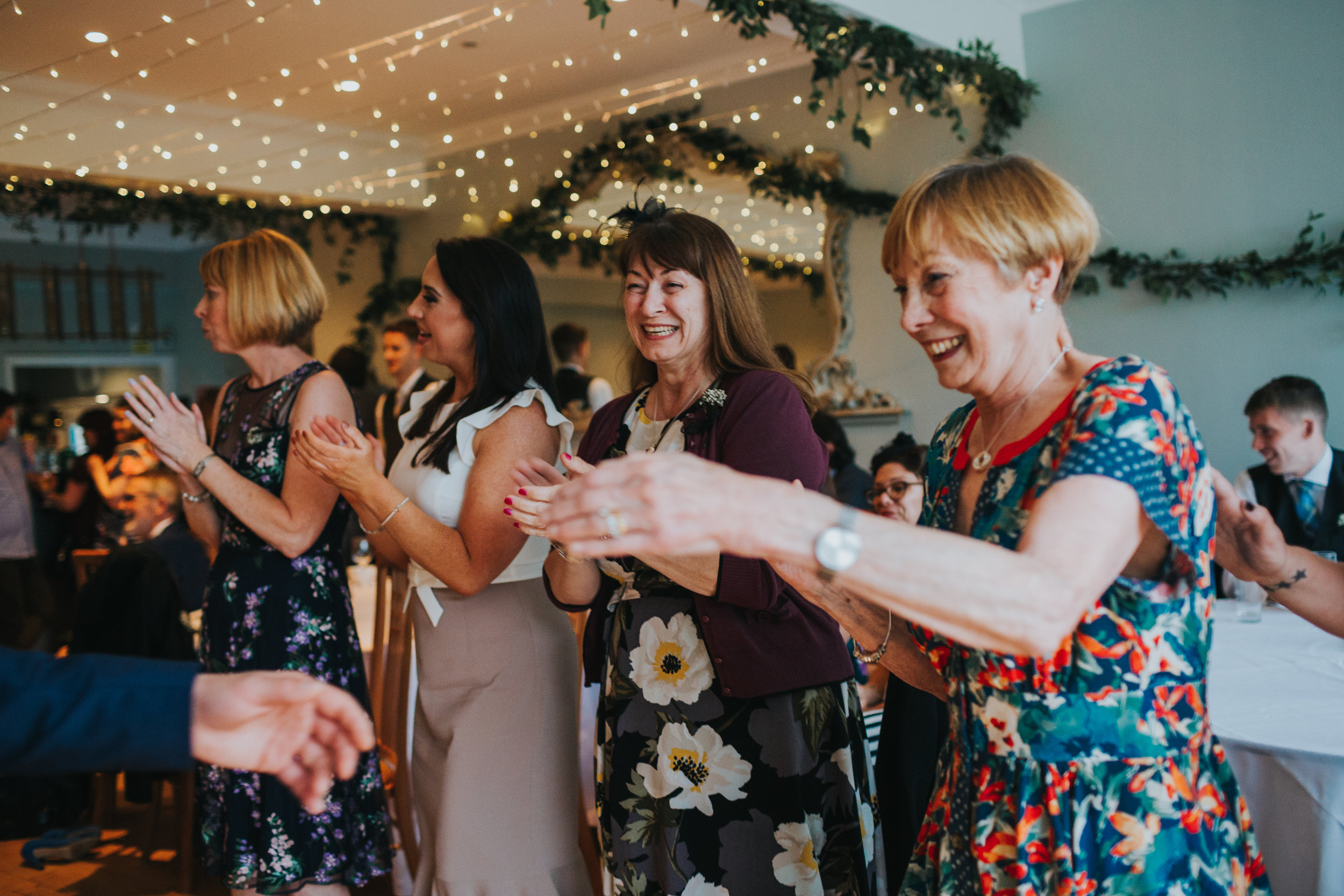 Wedding guests clap on edge of dance floor. 