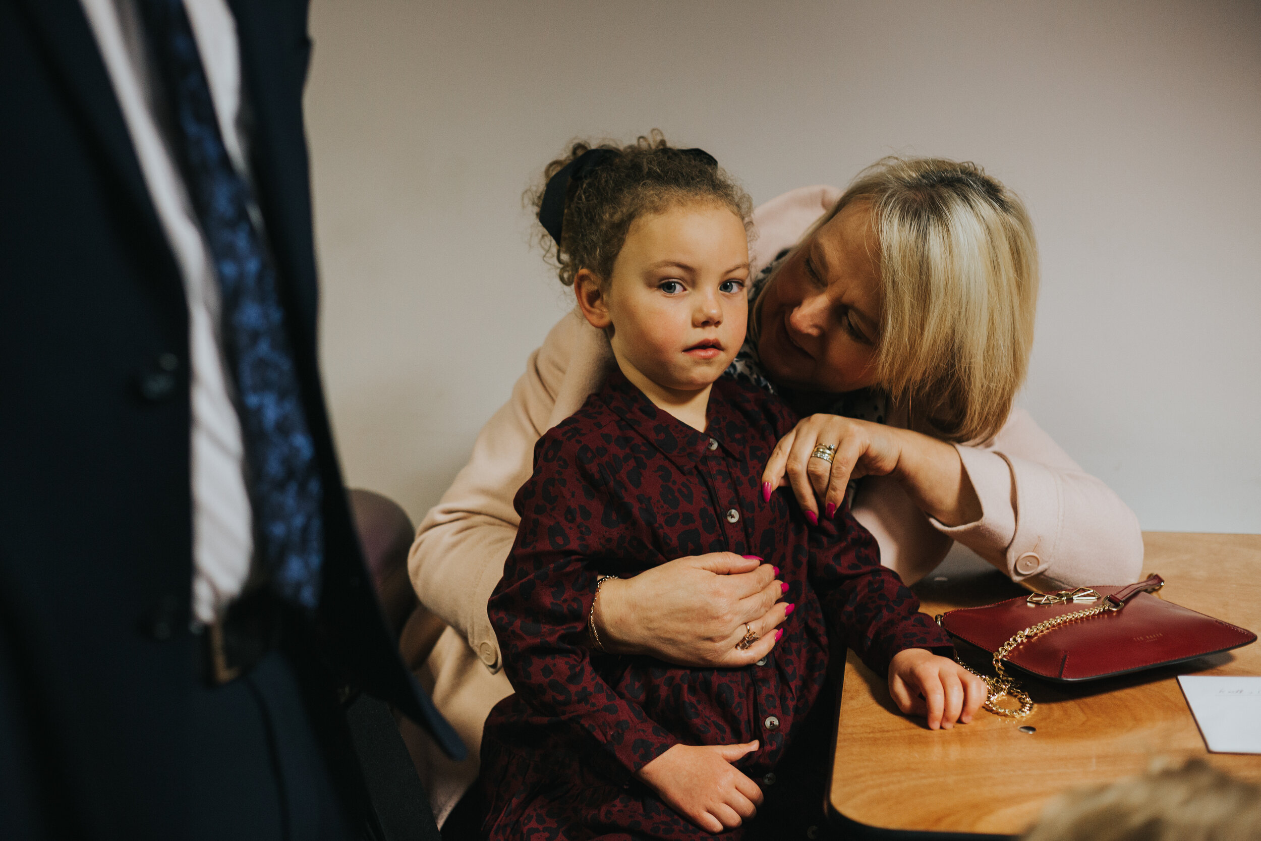 Little girl looks into the camera while  sitting a family members lap.   (Copy)