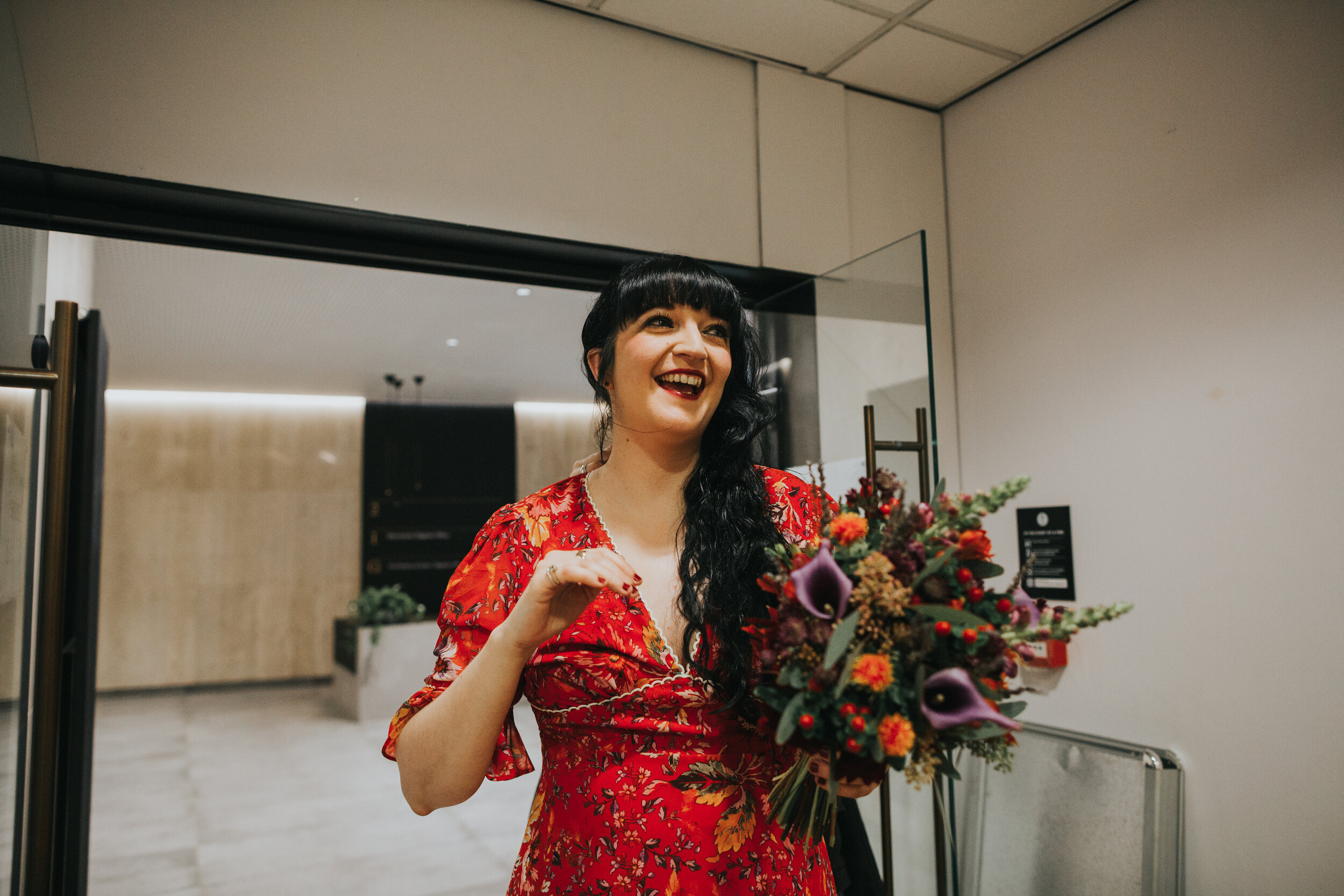 Bride wearing a read dress with a colourful red, purple, orange and green bouquet.  (Copy)