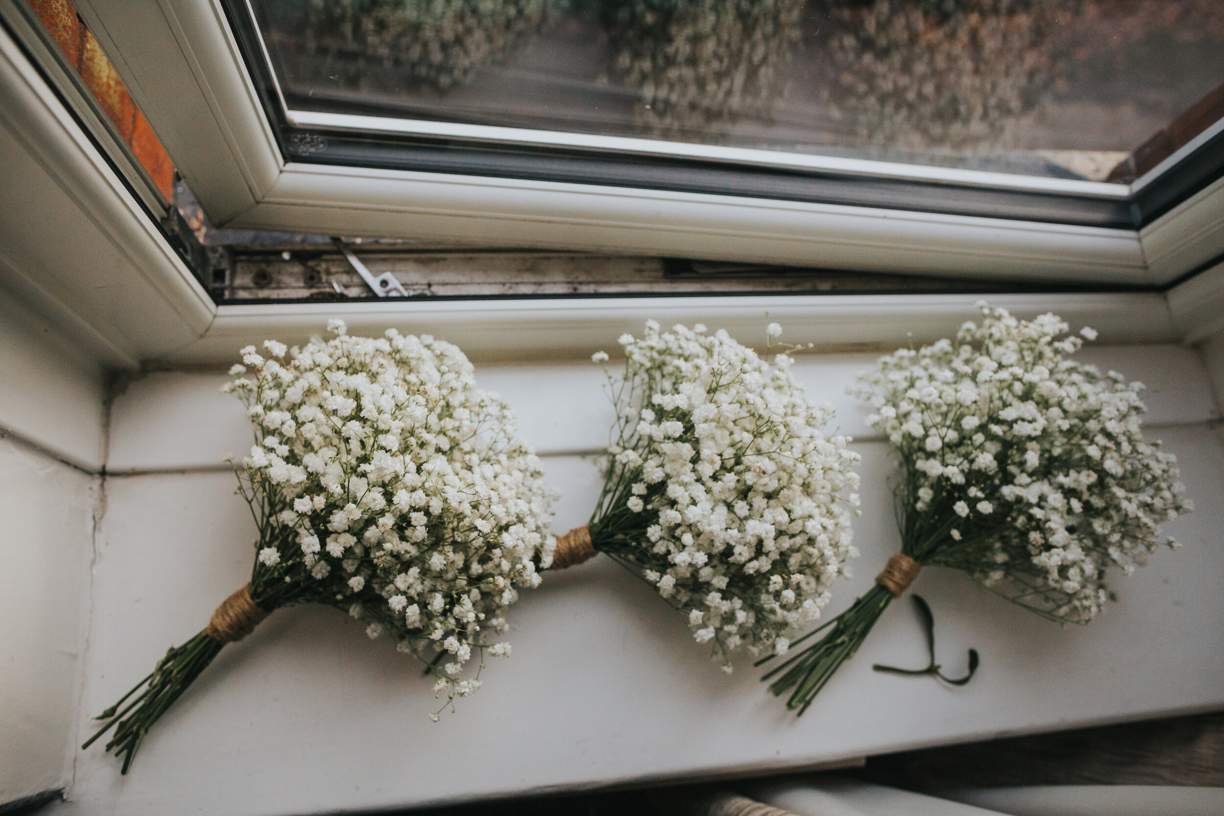 3 gypsey grass bouquets sit on a wintery windowsill. 