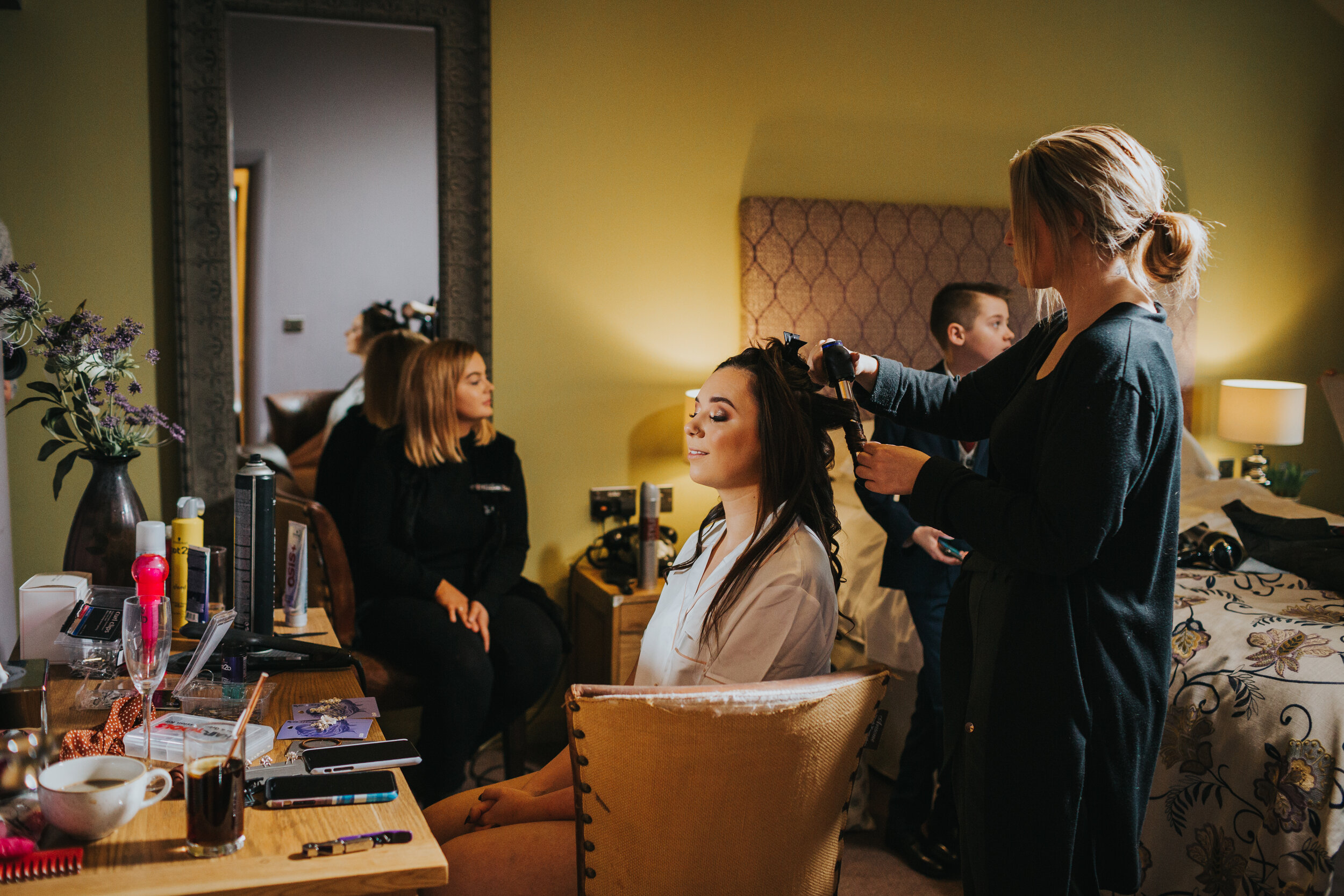 Bride smiles as she gets her hair done at her winter wedding in Lydgate