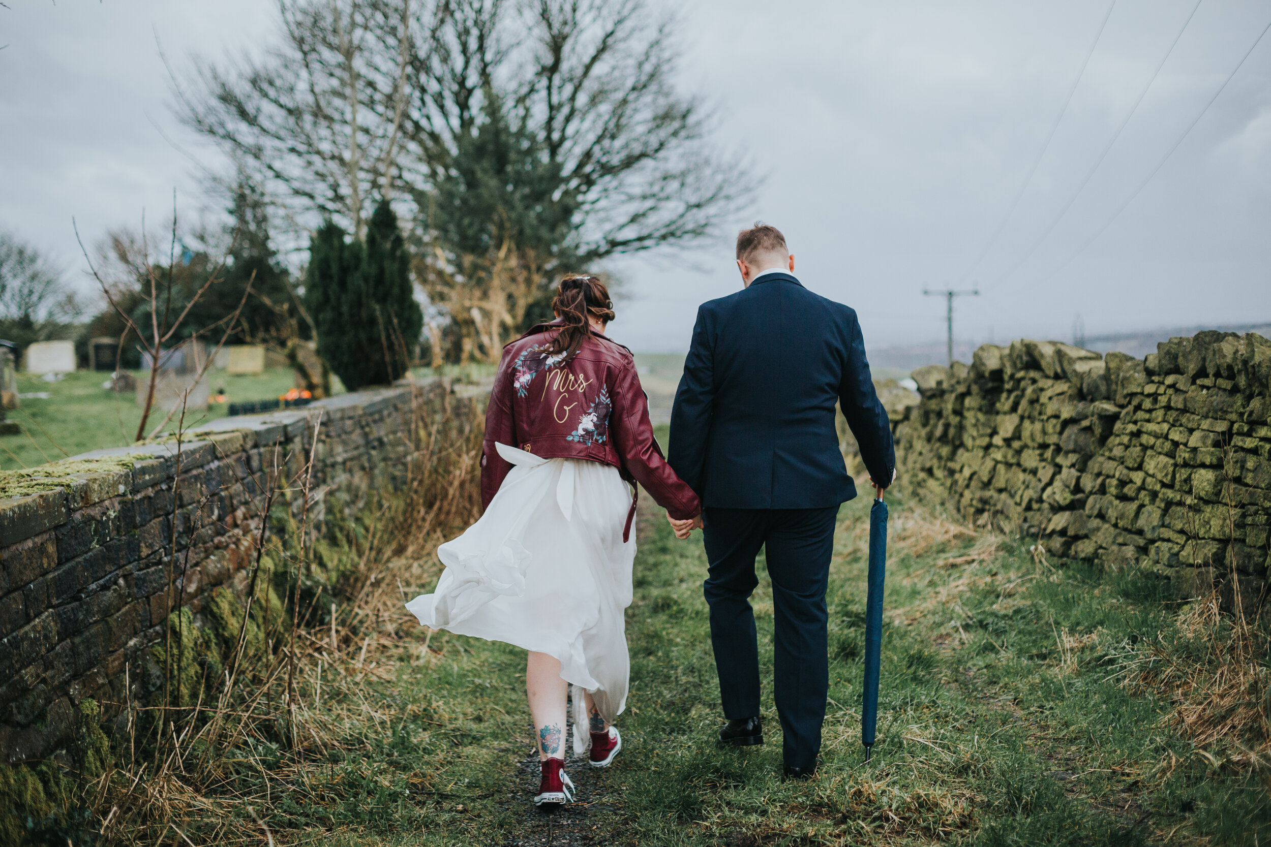 Bride and groom walk down a country lane together. 