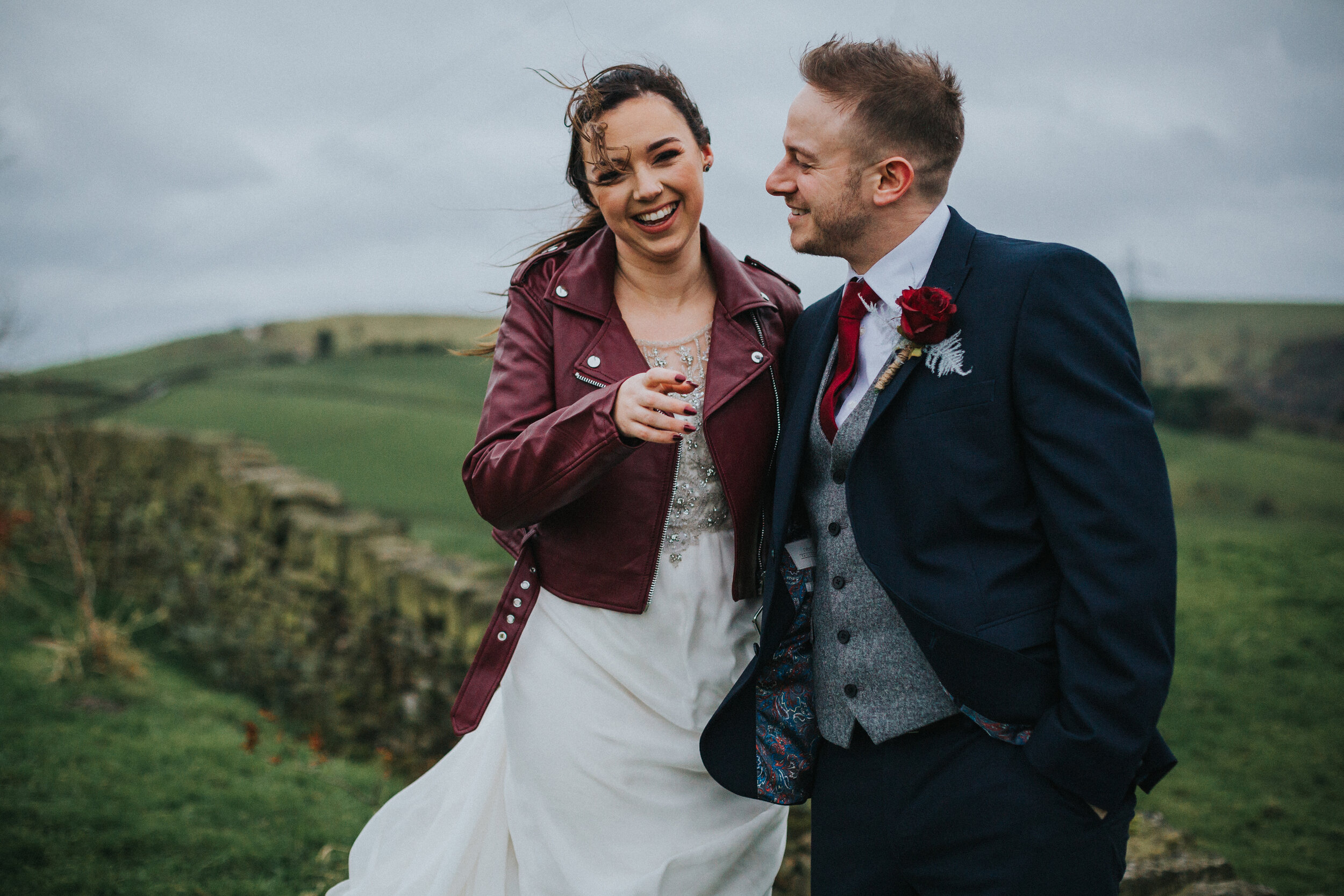 Bride and groom laughing together in the wind. 