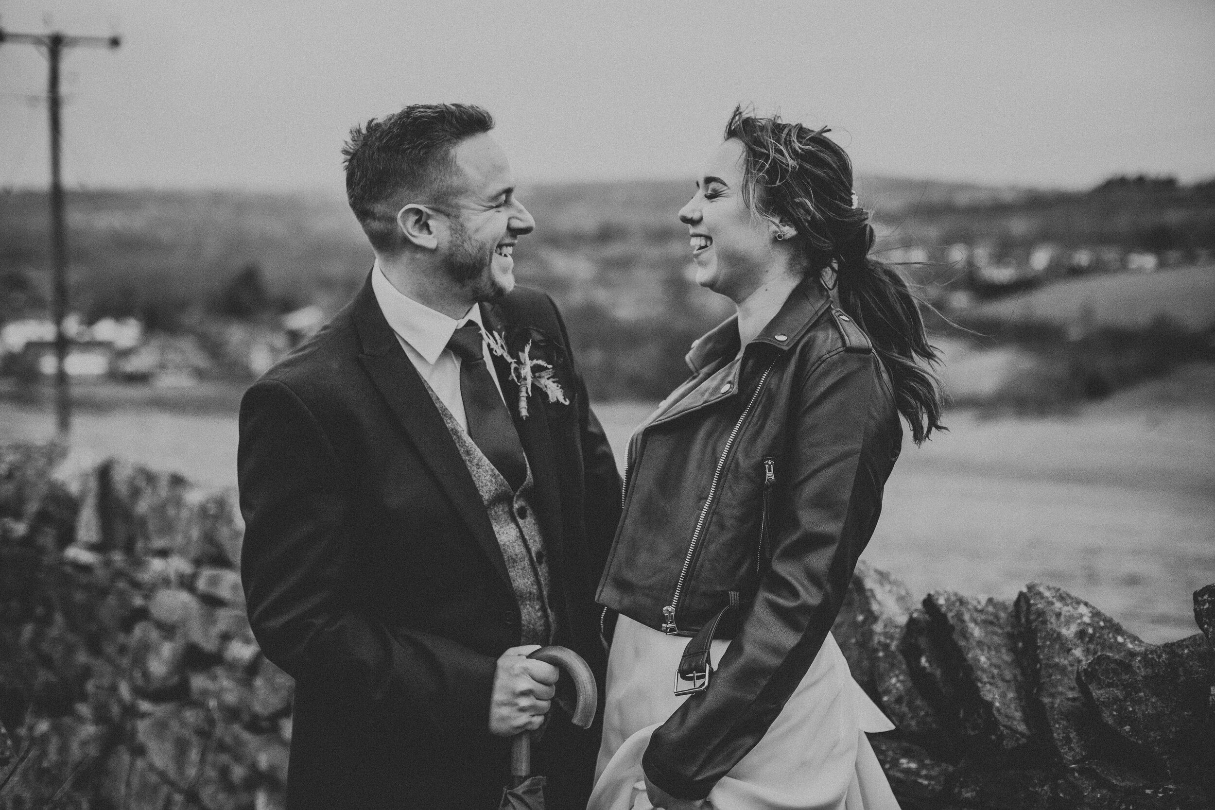 Bride and Groom laugh together with the rolling hills of Lydgate behind them. 