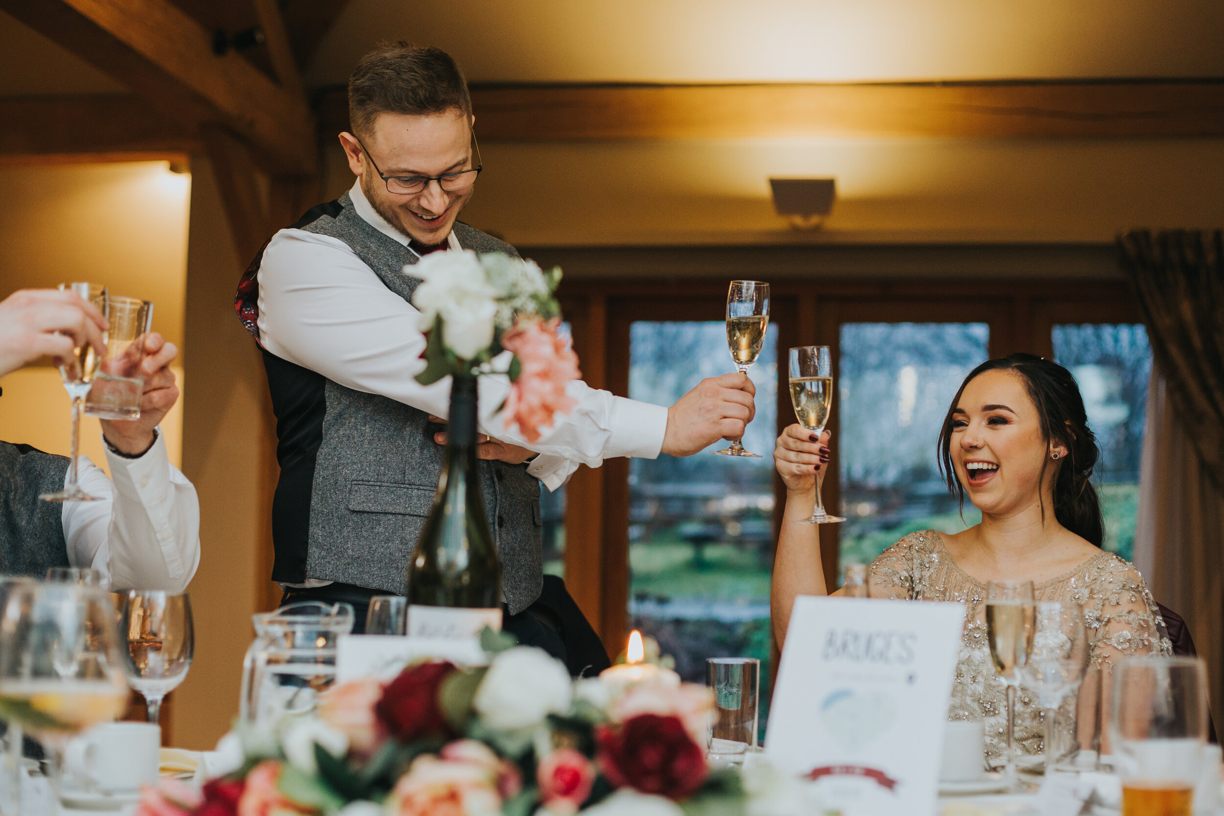 Bride and Groom clink their glasses laughing. 