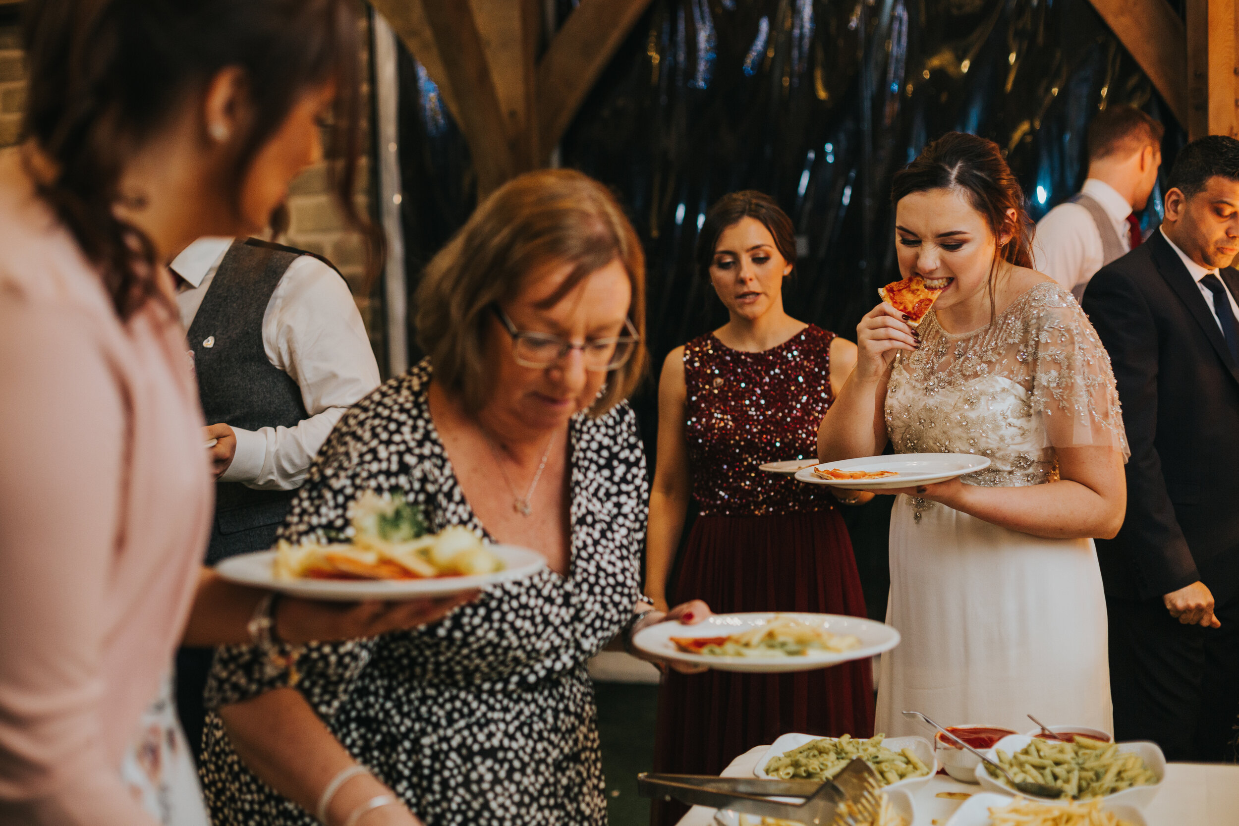 Bride takes a bite from her pizza. 