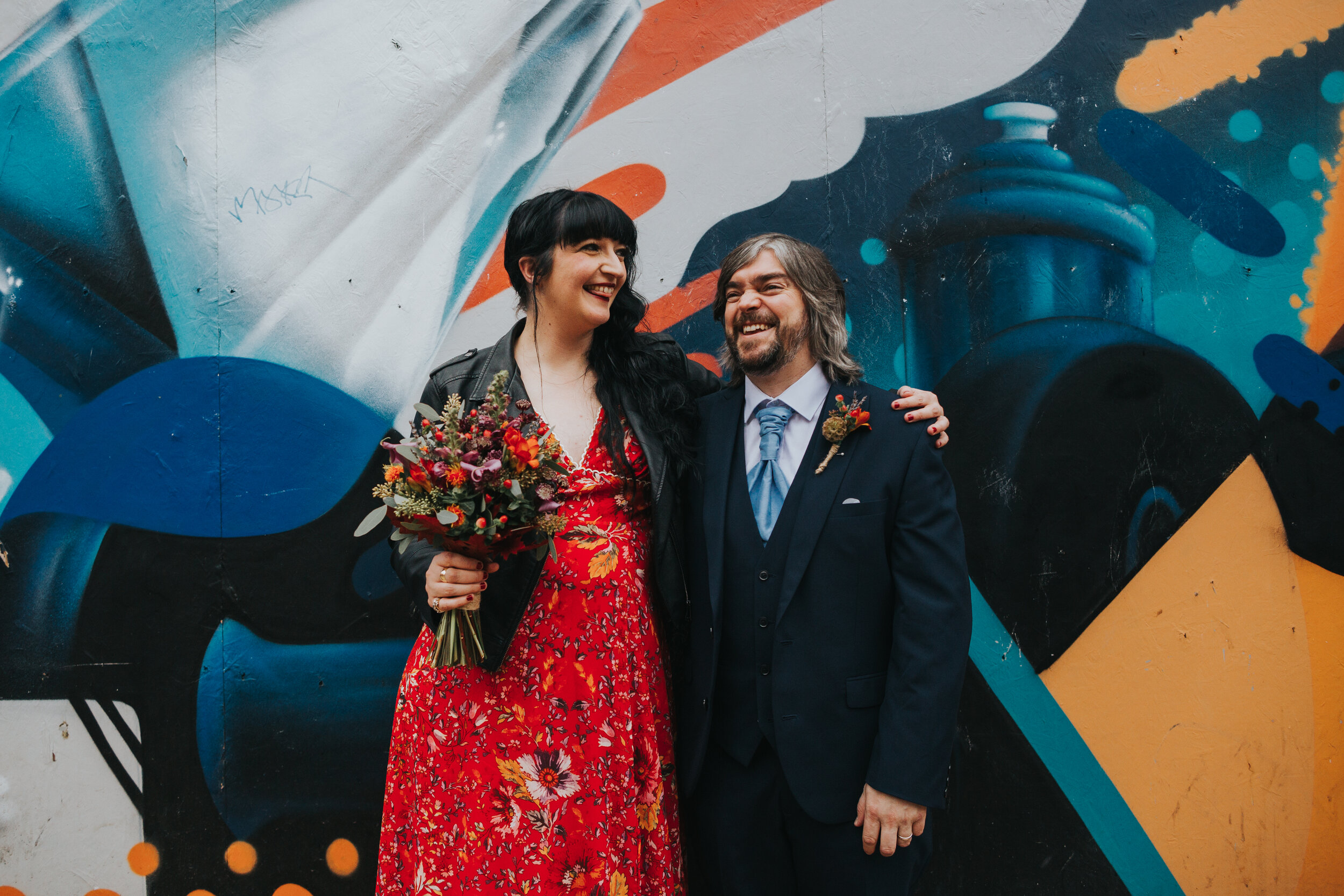 Bride and groom laughing in front of some graffiti in Manchester.  (Copy)