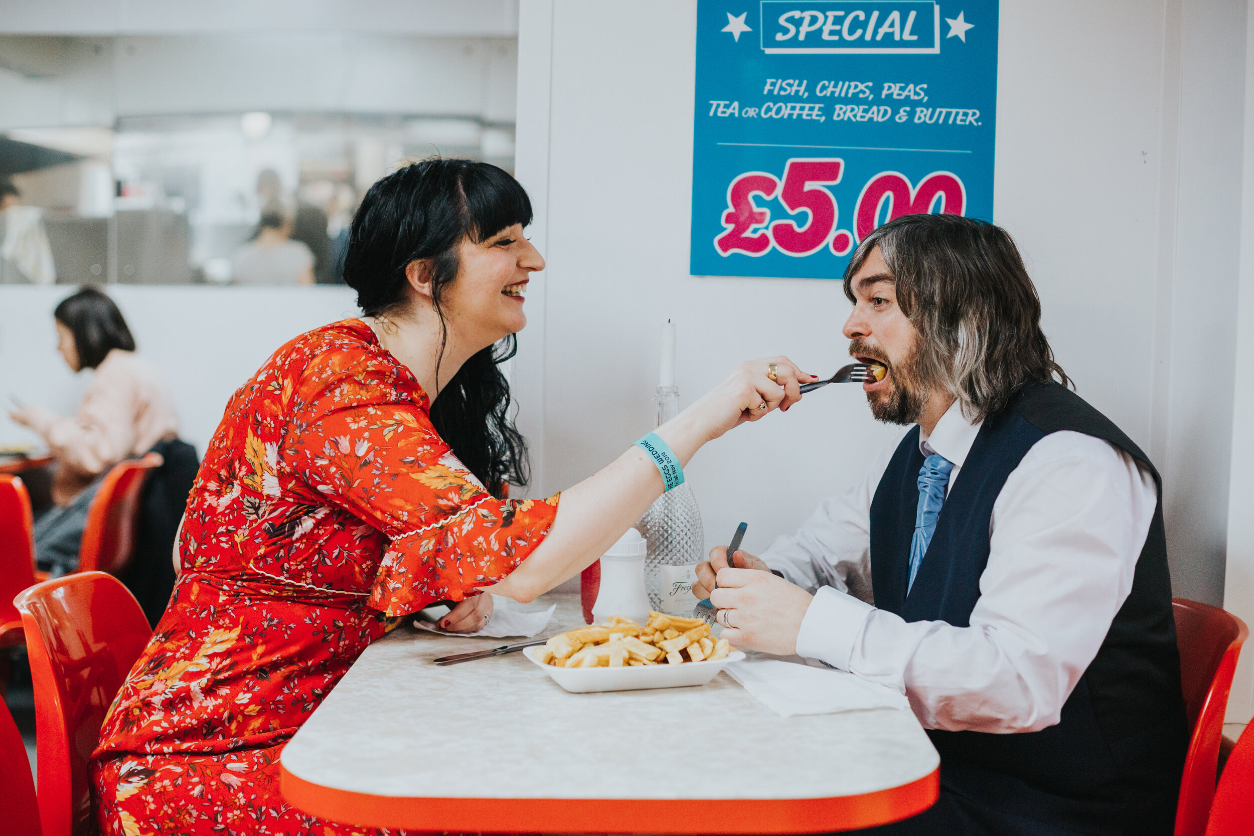Bride feeds groom a chip in the chippy on their wedding day, (Copy)