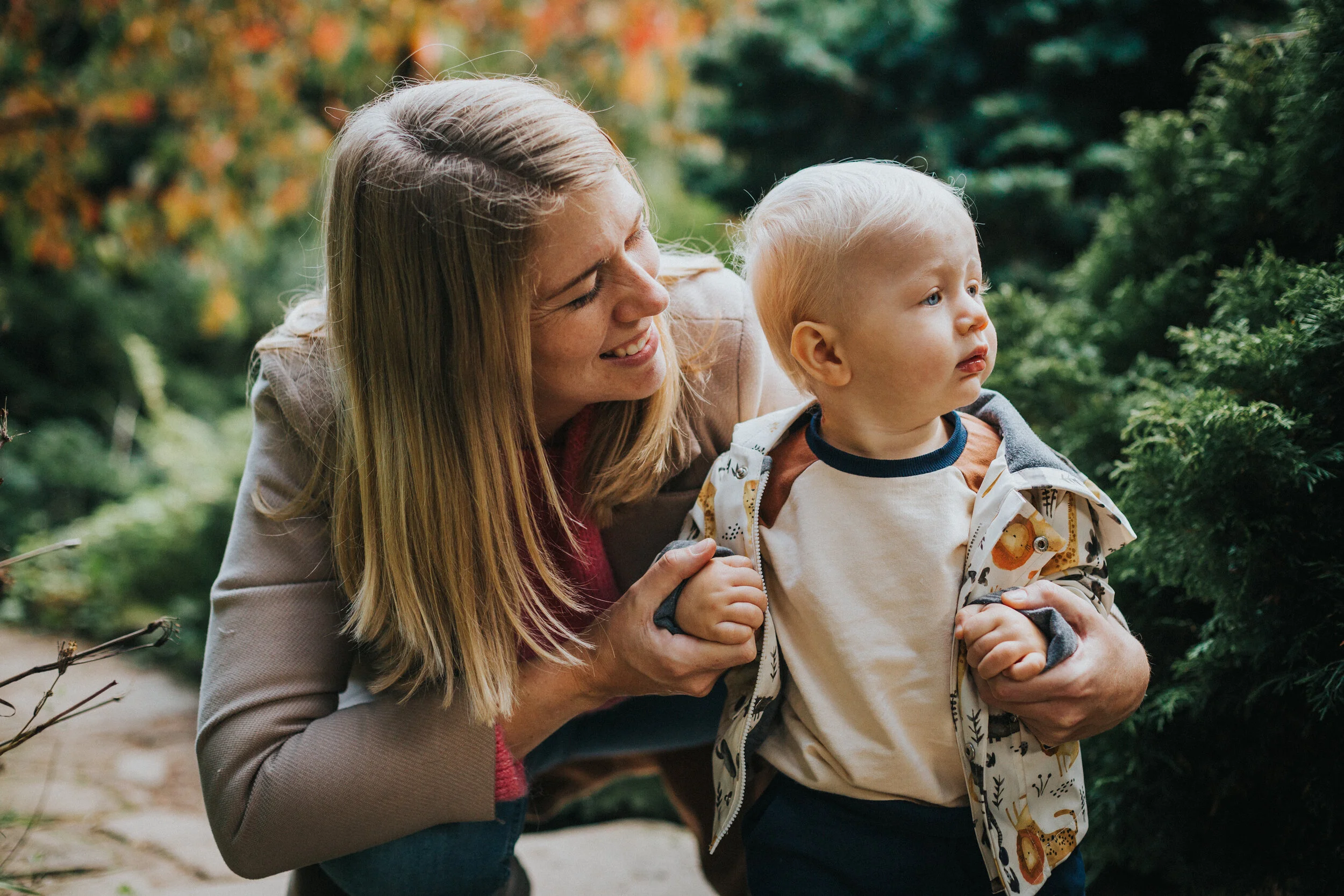 Mum holds her little boy as he walks and takes in nature. 