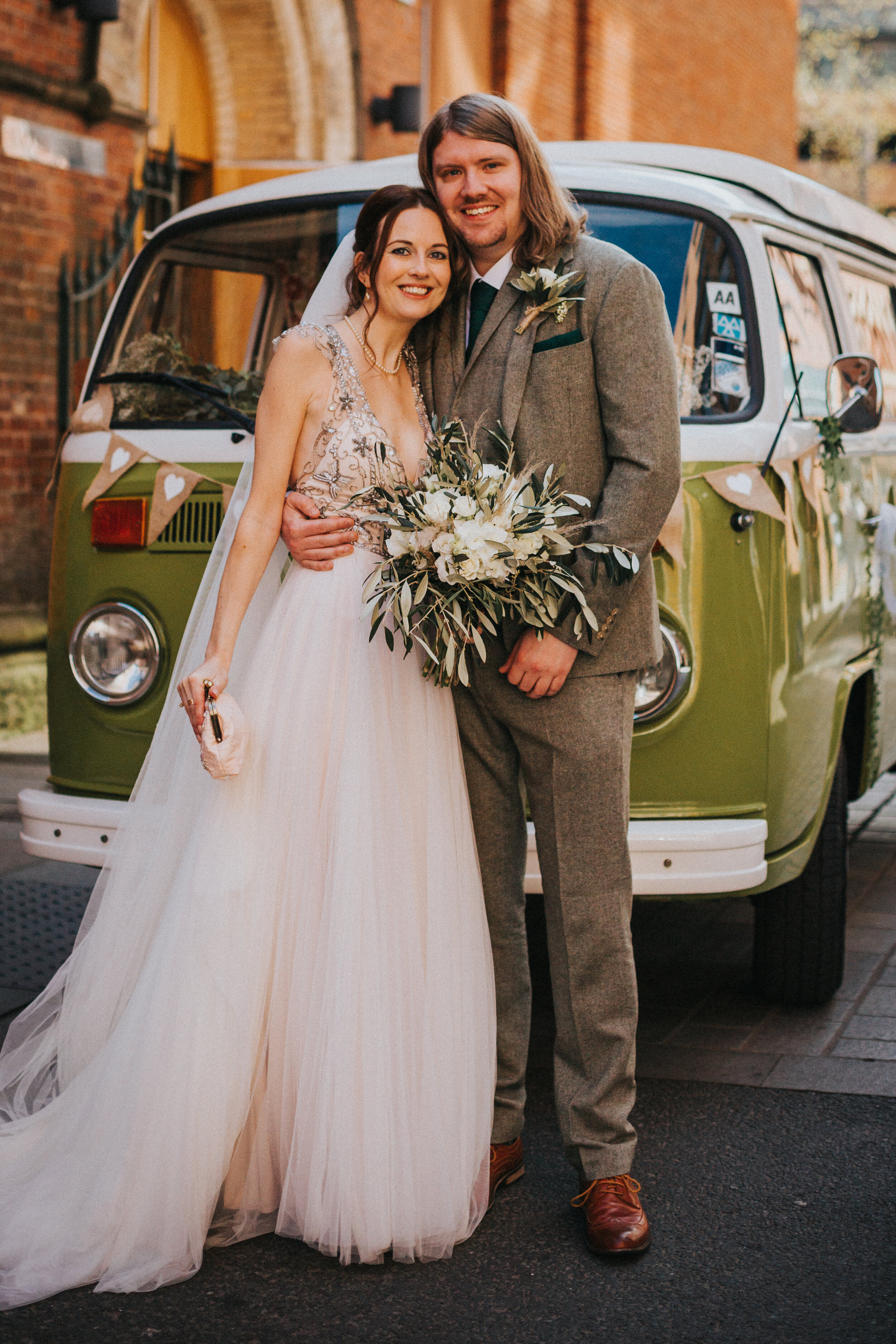 Bride and Groom stand together in front of their green VW camper van