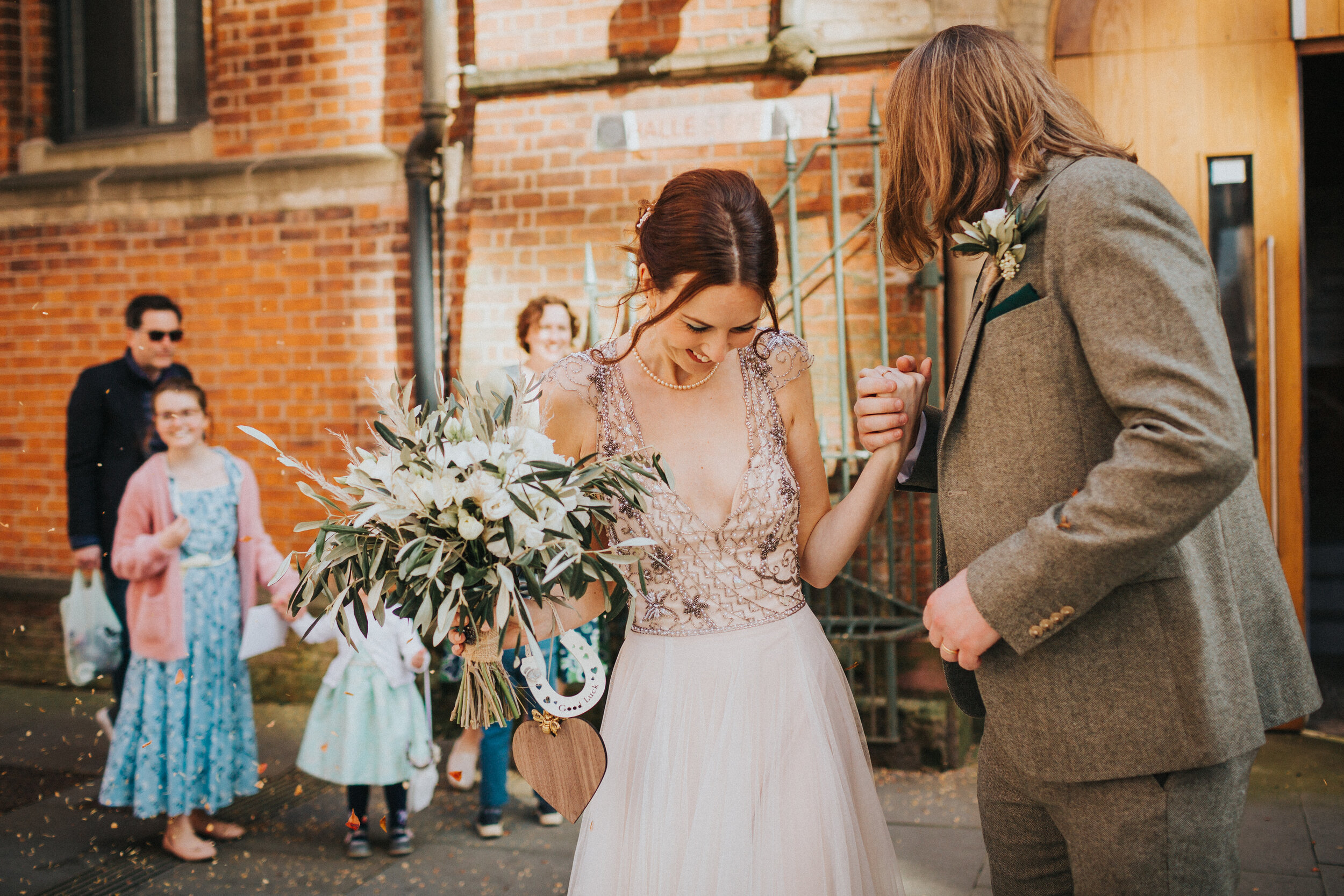 Bride and Groom laugh as they have confetti thrown at them. 