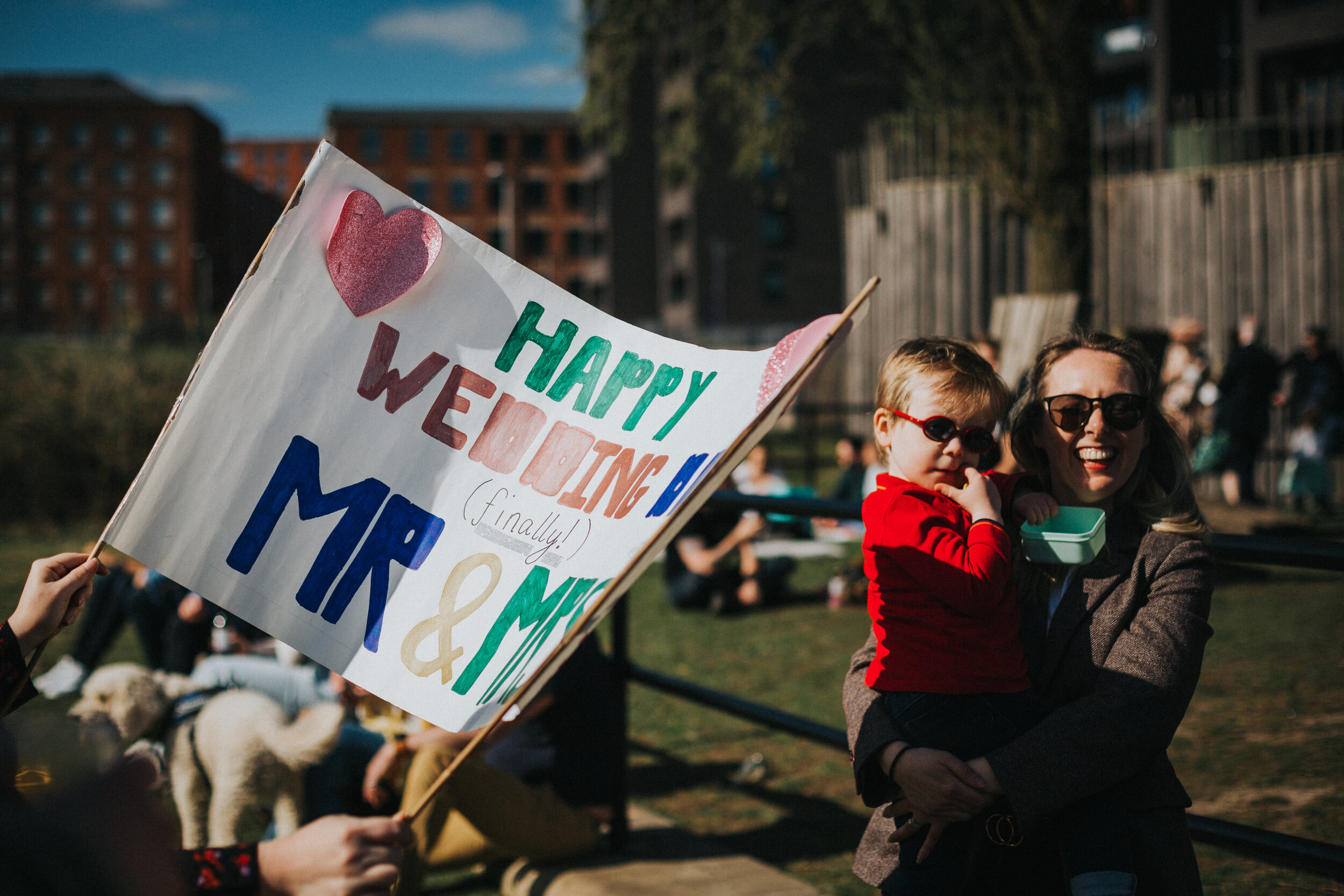 Hand made wedding sign in foreground of mother and child who made the sign, un posed. 