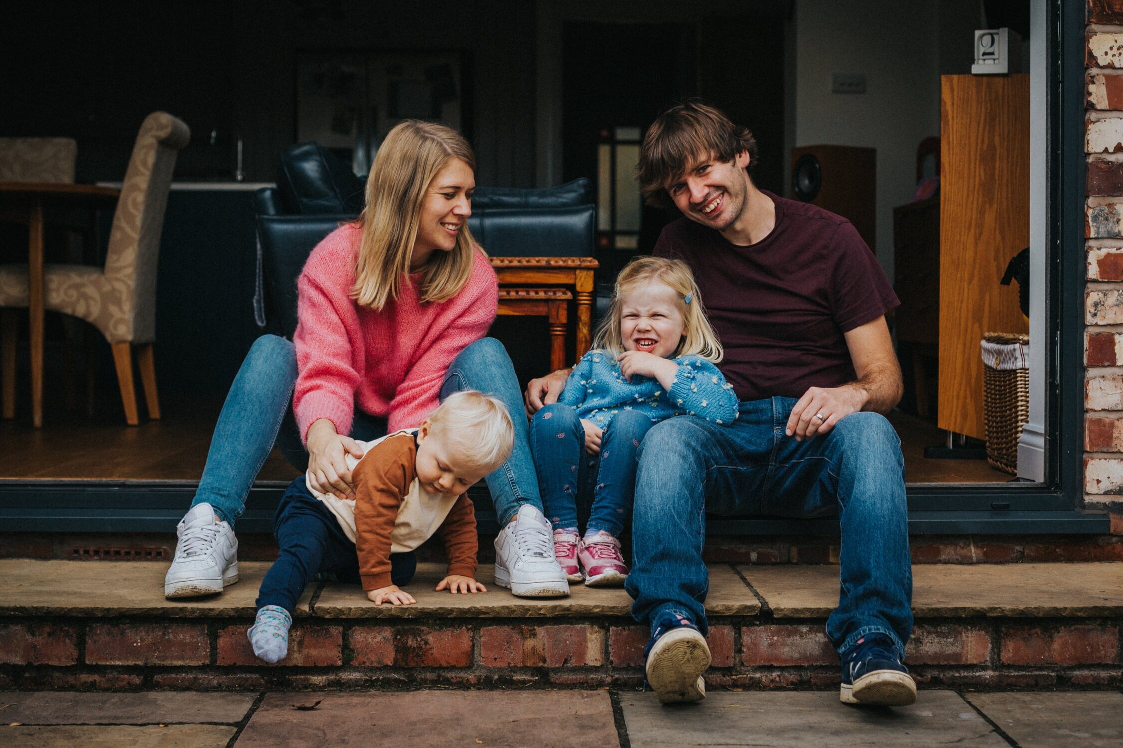 Family have a relaxed photo together on the back steps of their home in Didsbury. 