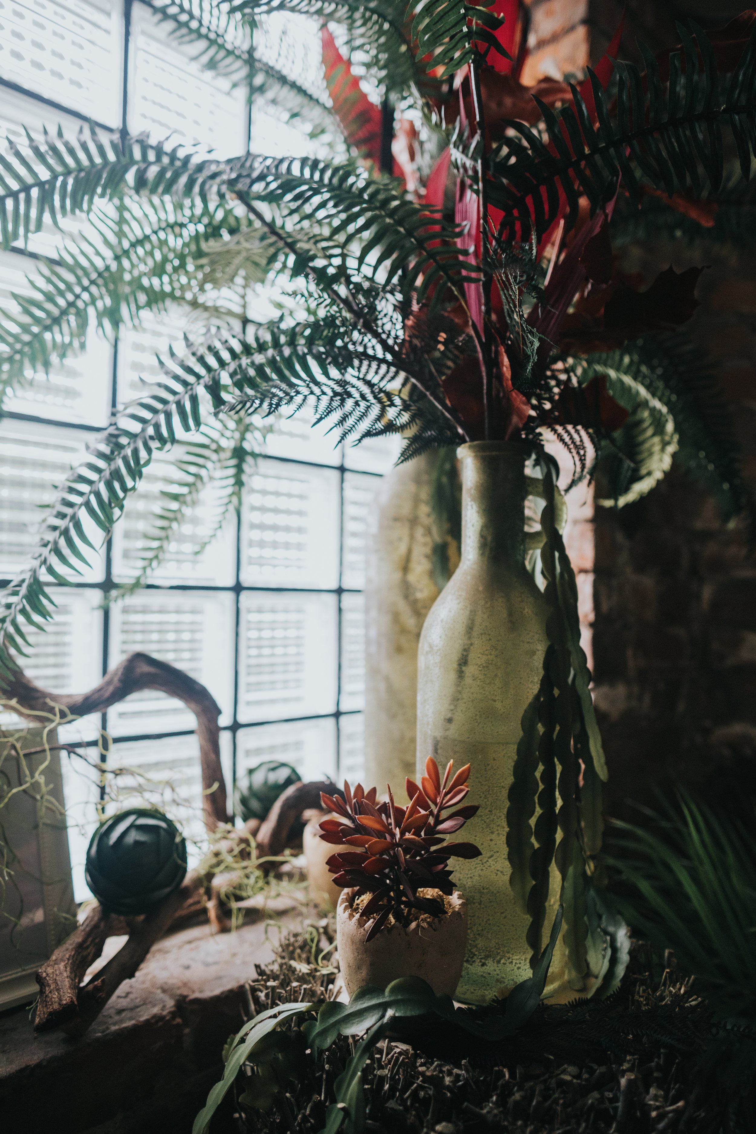 Vase and jungle foliage next to industrial glass window