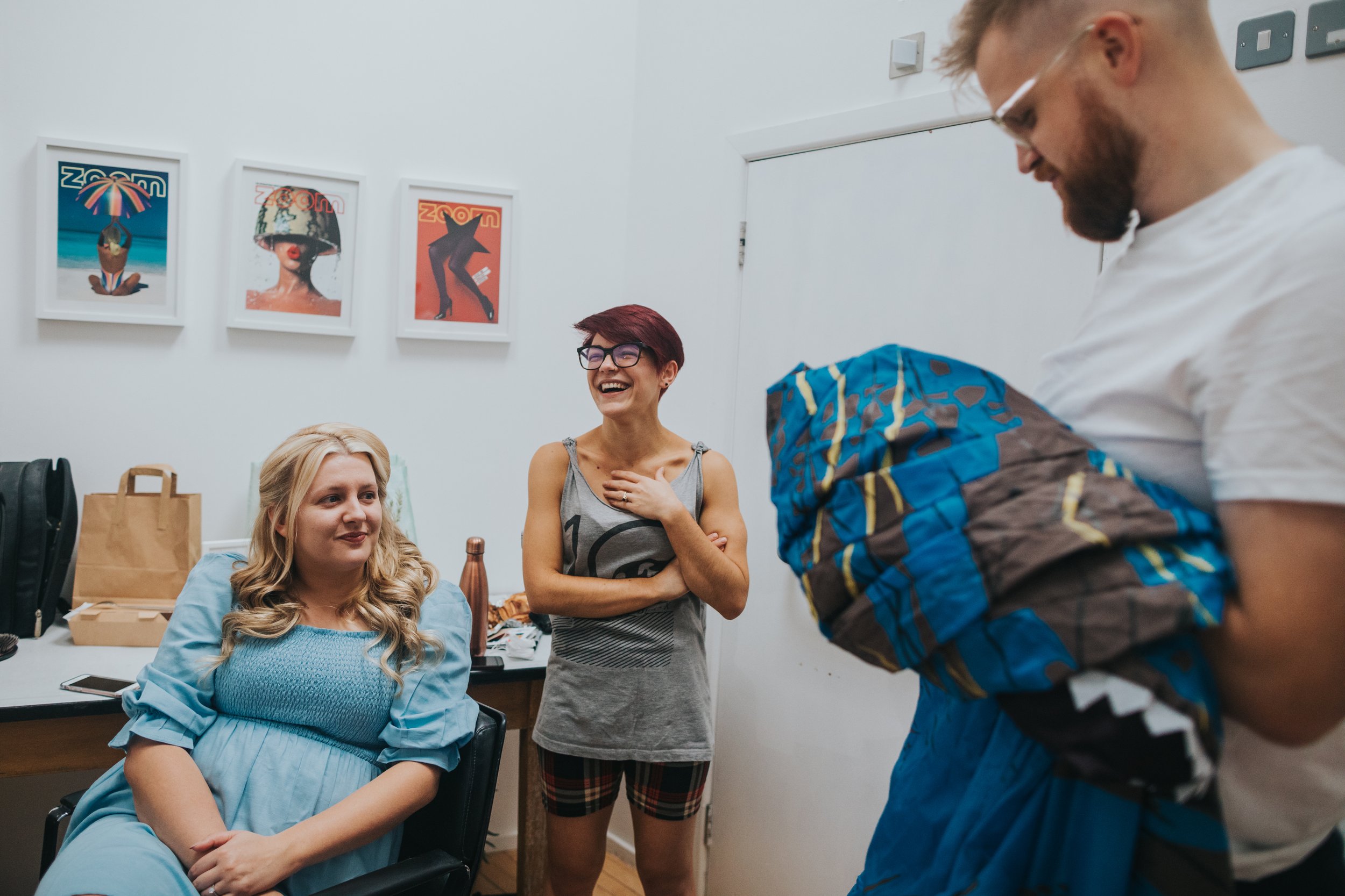 Bride laughs as her friend tries on a dinosaur costume. 