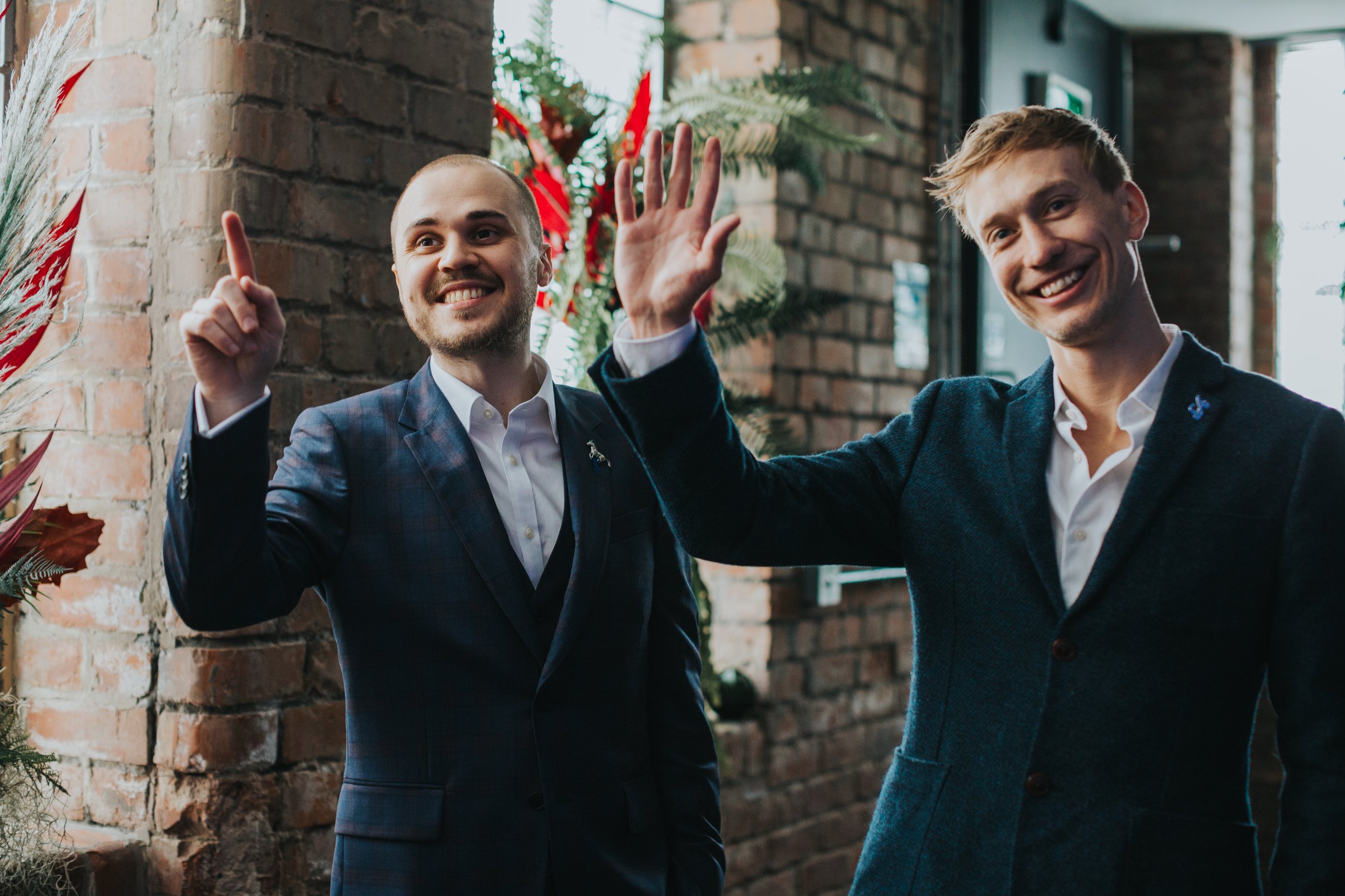 Groom and best man wave at guests. 