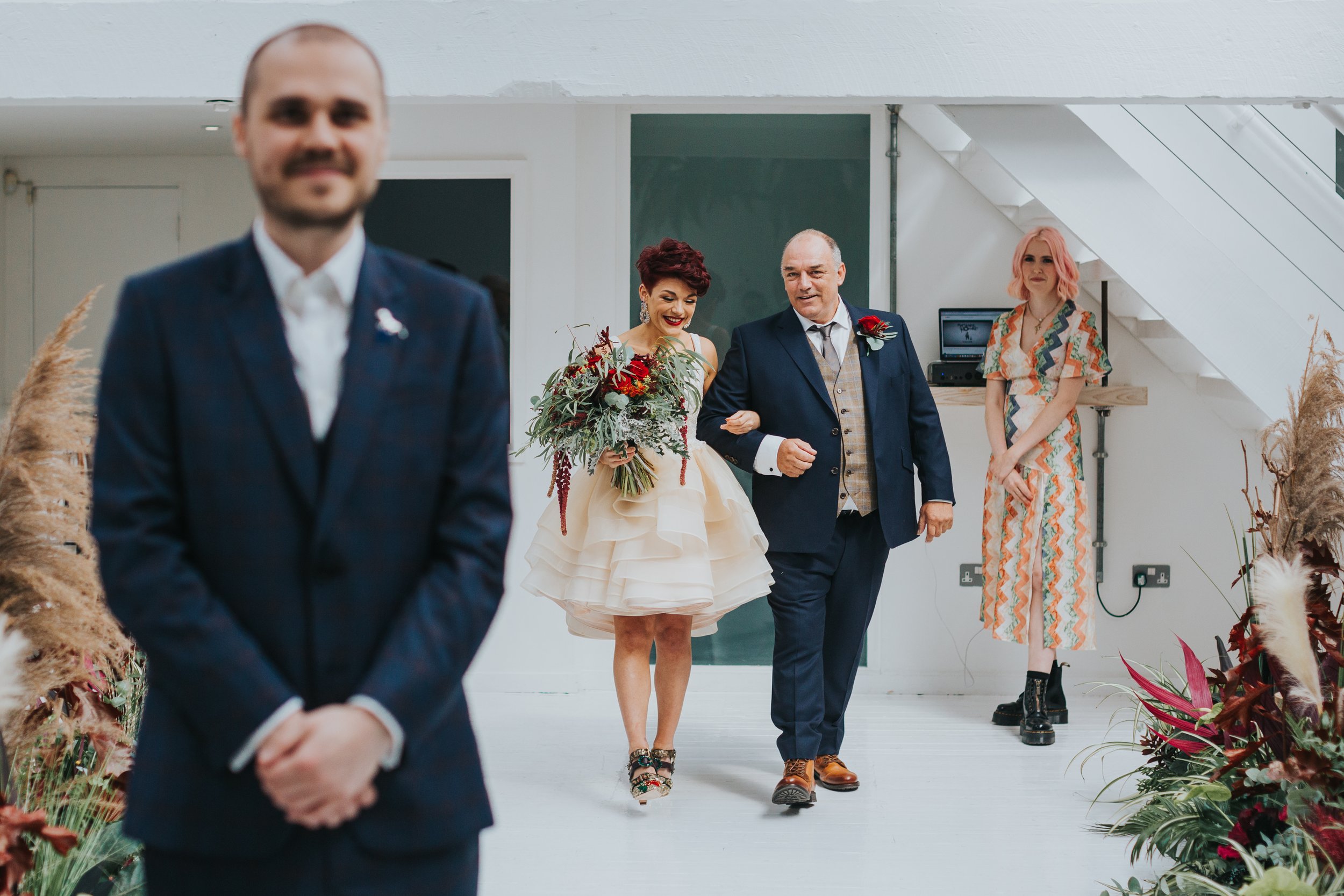 Bride is walked down the aisle by her father. 