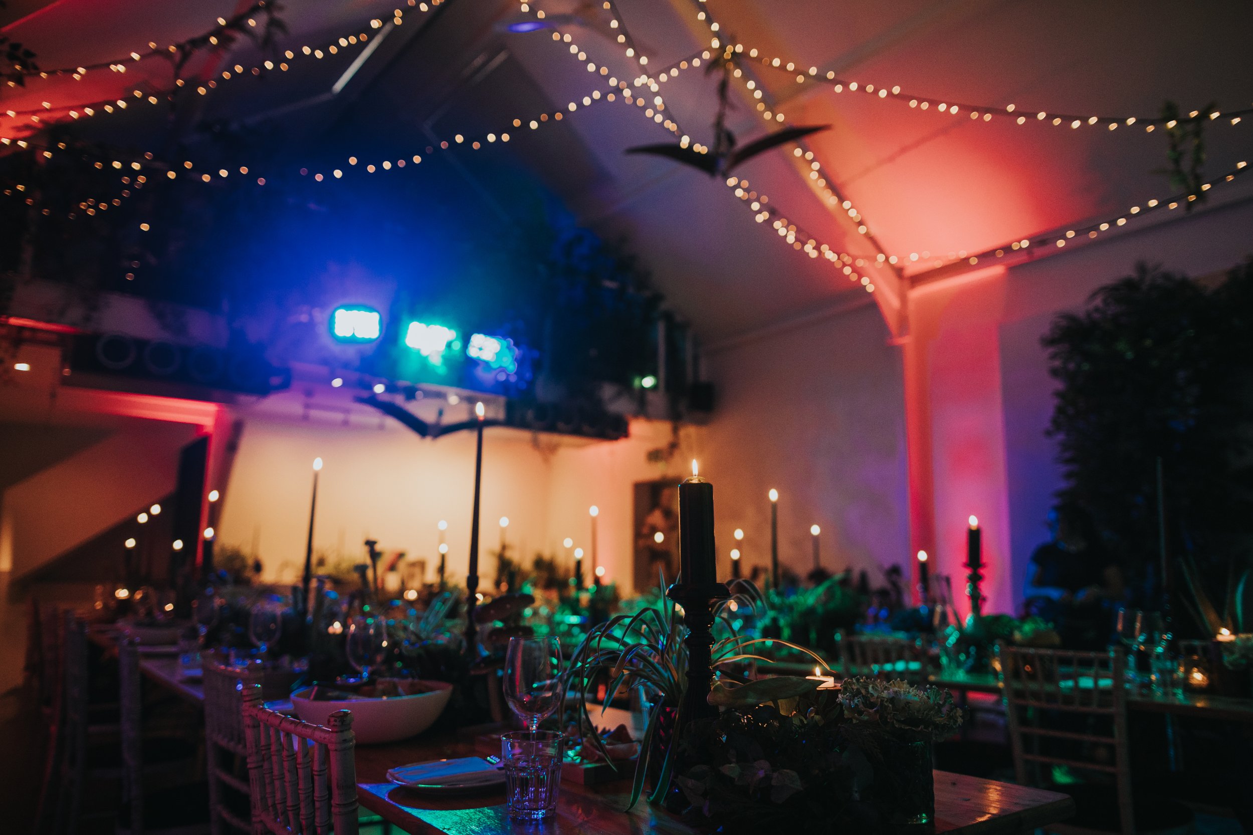 Dramatically lit banquet hall in blue, pink, yellow and green. 