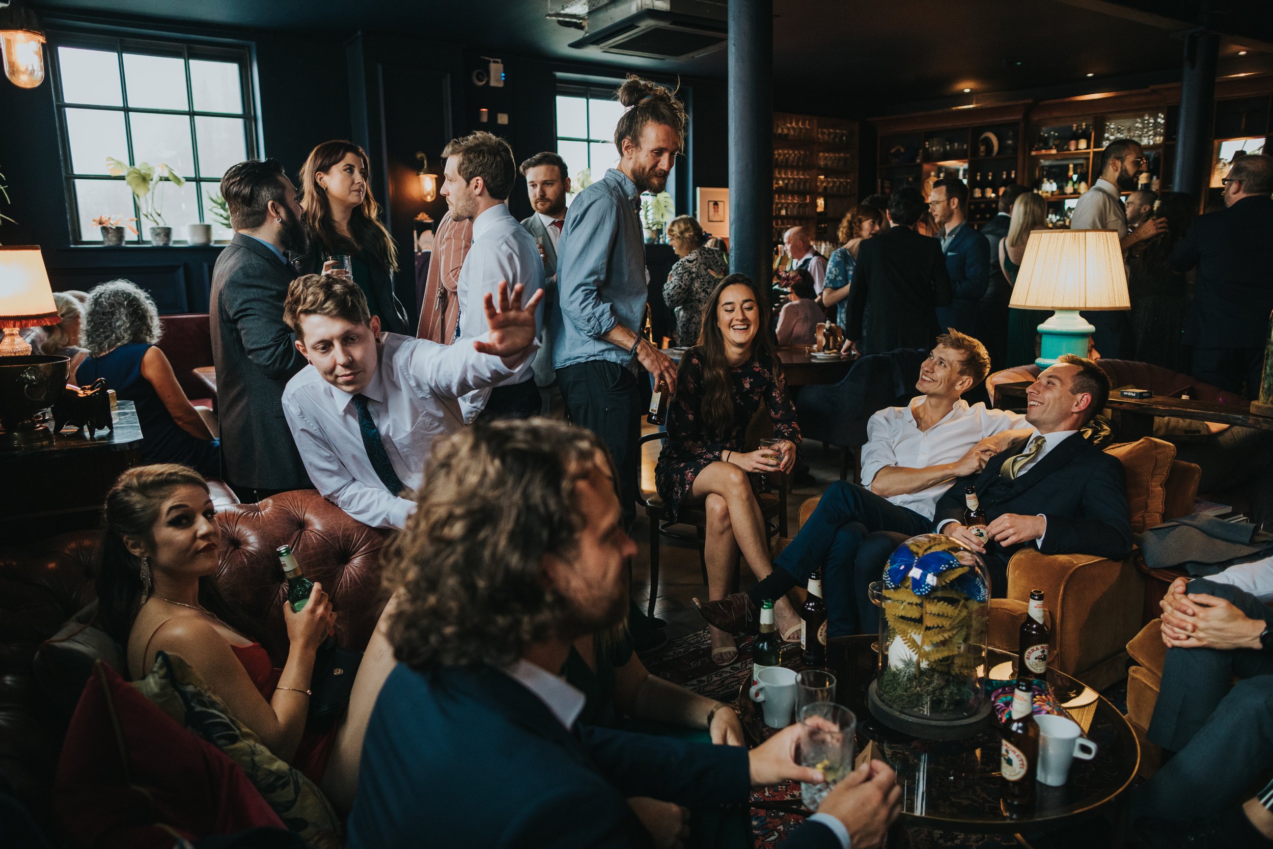 Long shot of everyone sitting down chatting in the bar. 