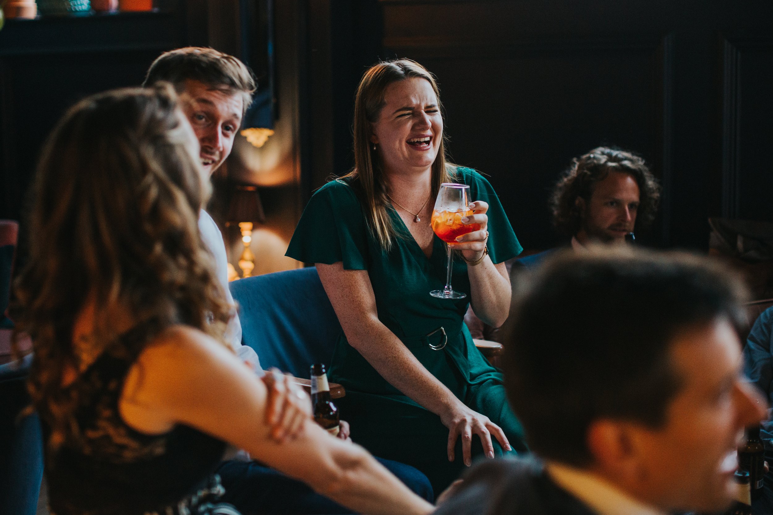 Guest laughing with a cocktail in her hand. 