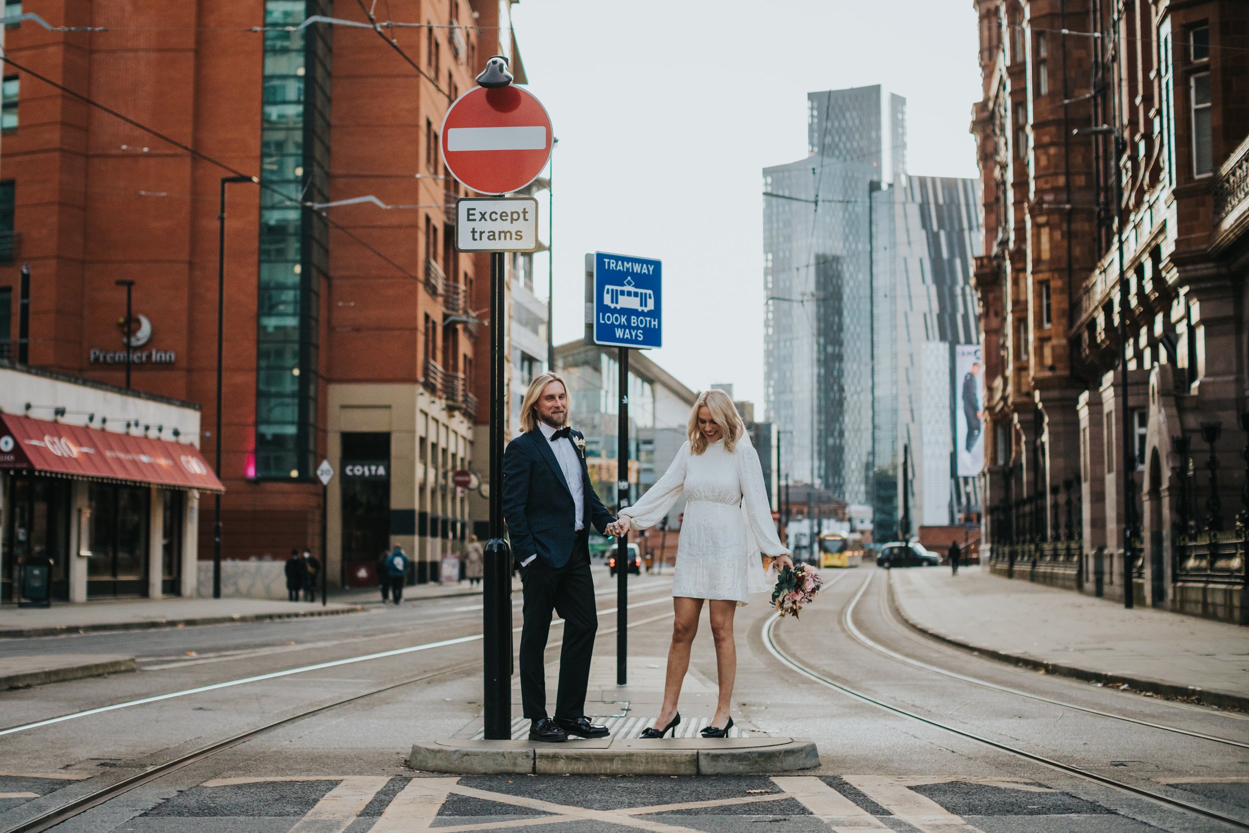 Bride and groom casually stand together in Manchester City Centre