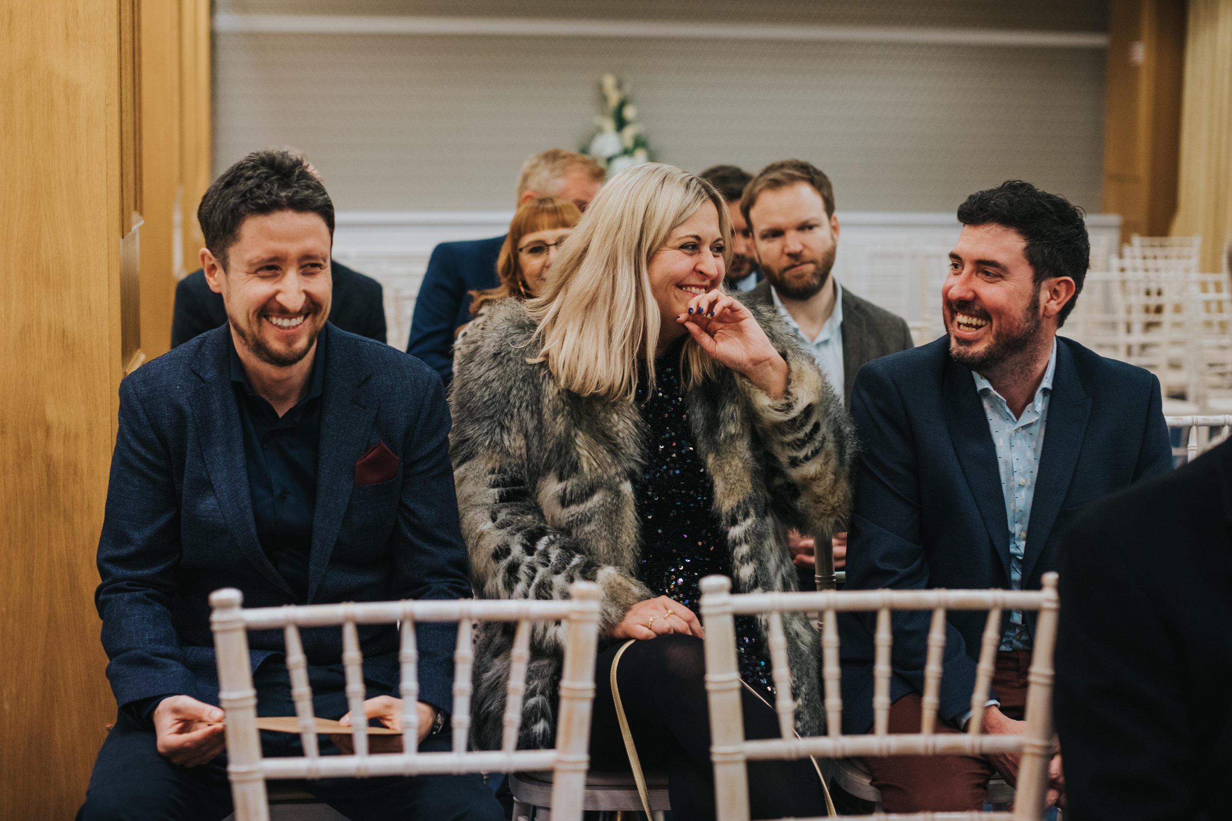 Wedding guests have a giggle in the ceremony room. 